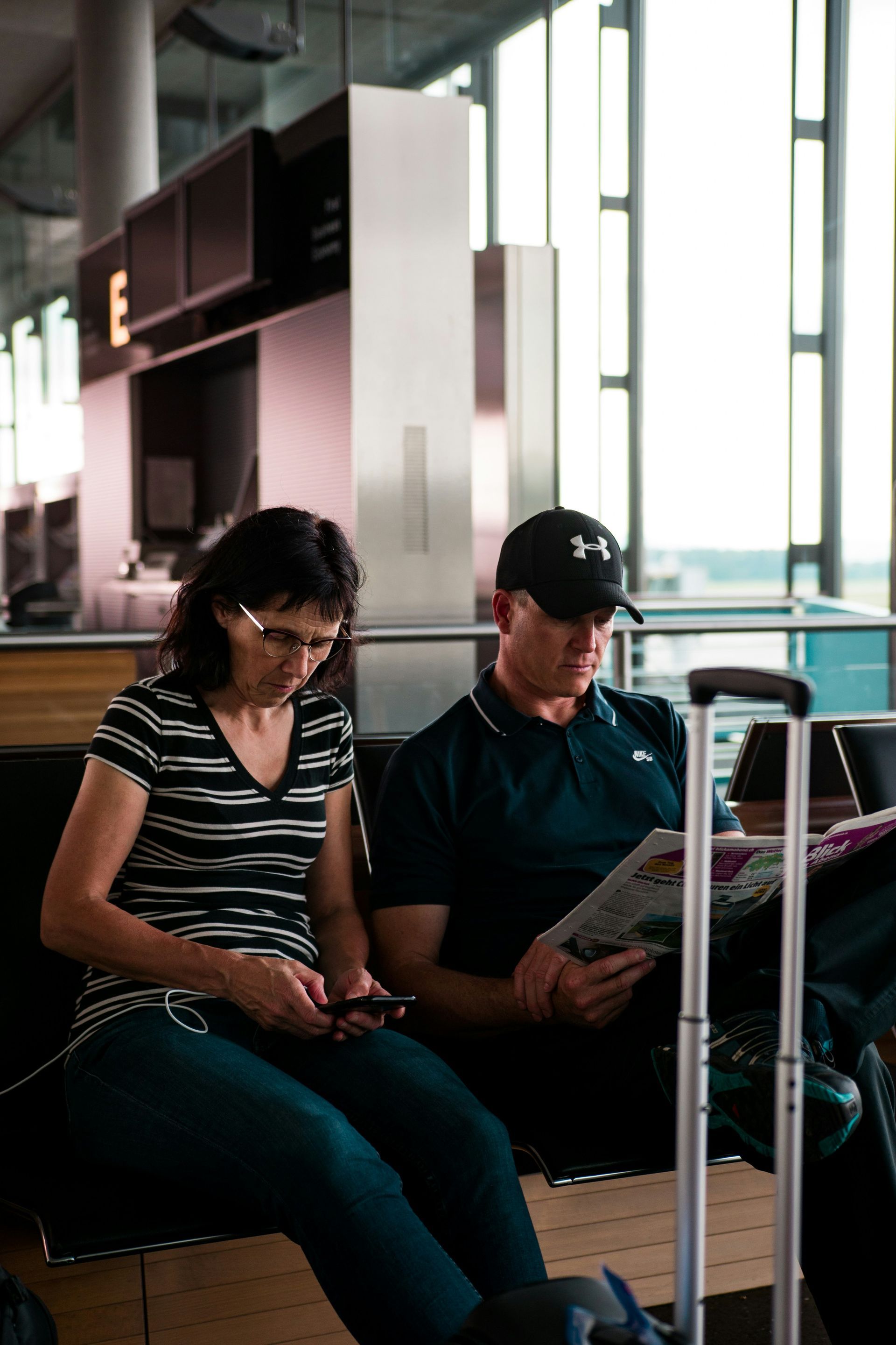 A man and a woman are sitting on a bench at an airport.