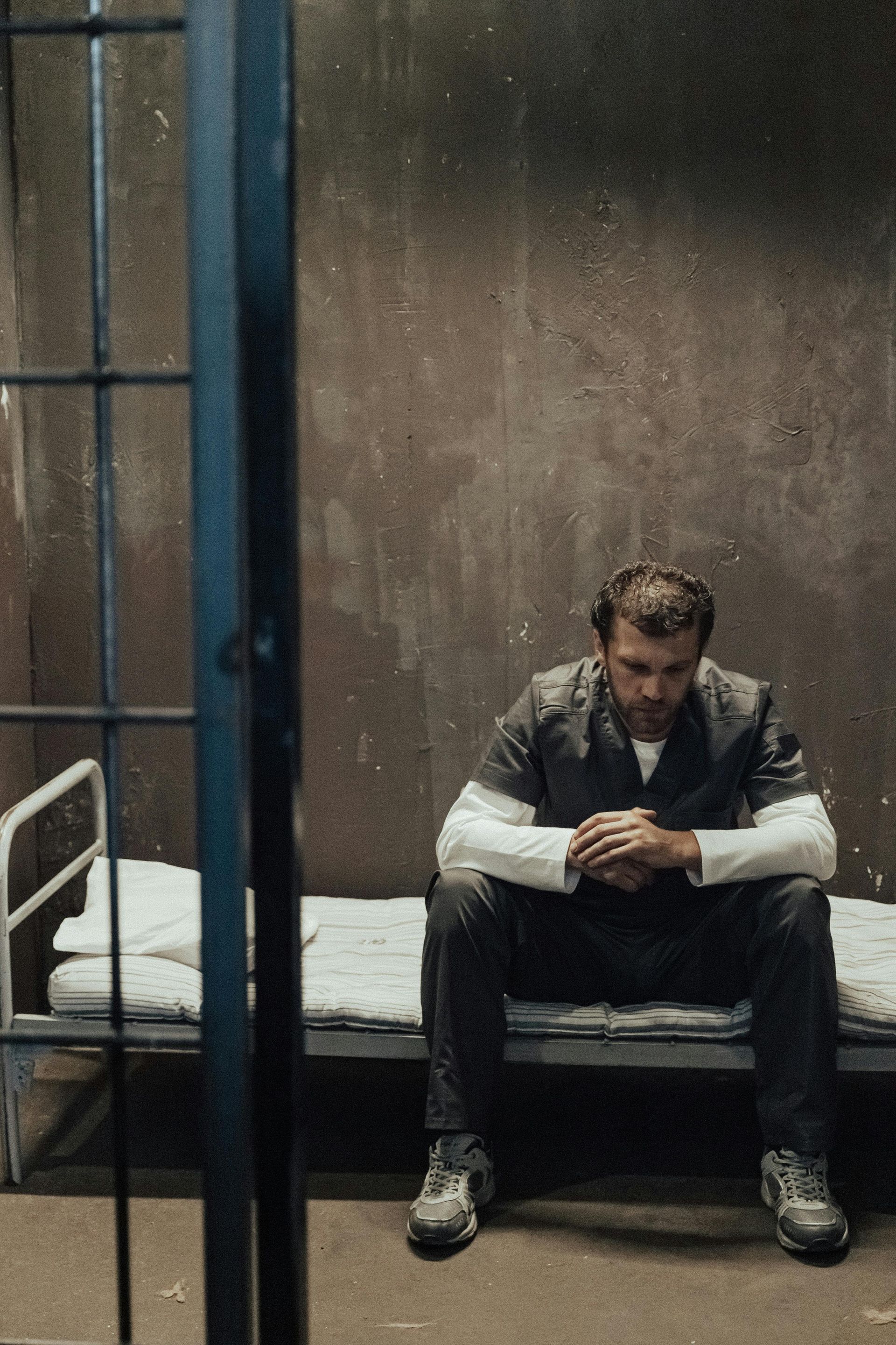 A man is sitting on a bed in a prison cell
