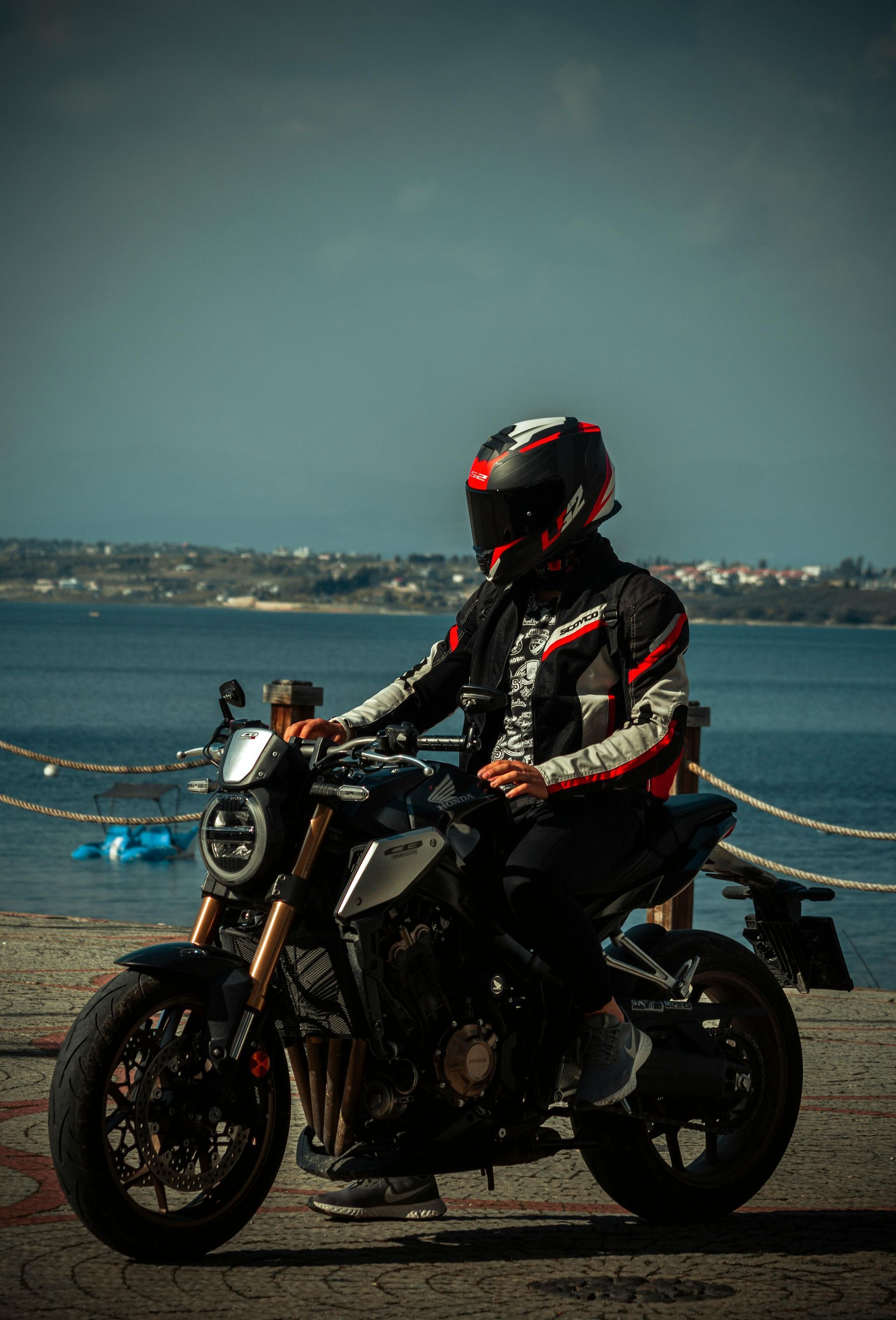 A man is sitting on a motorcycle next to a body of water.