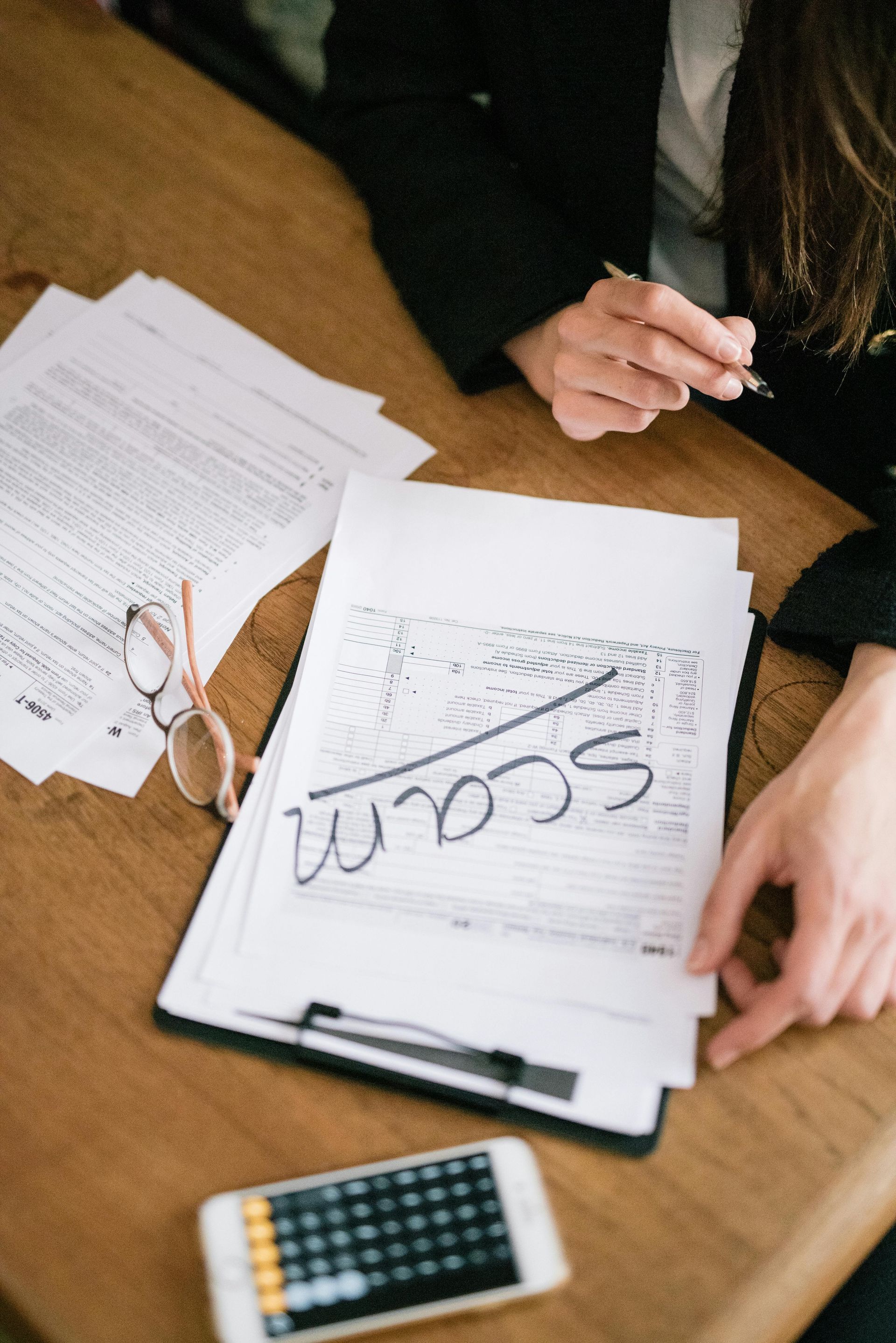 A woman is sitting at a table with papers and a calculator.