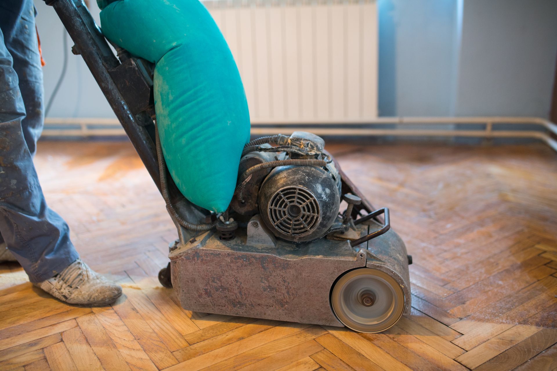 Floor refinishing professional sanding a hardwood floor with a floor sander