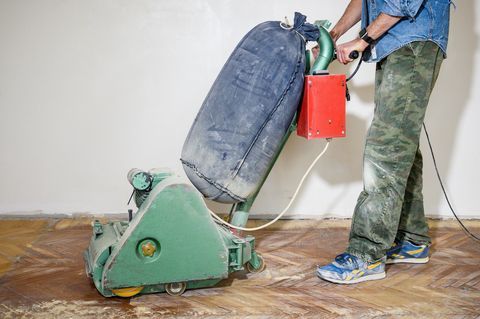 Worker floor sanding with floor sander