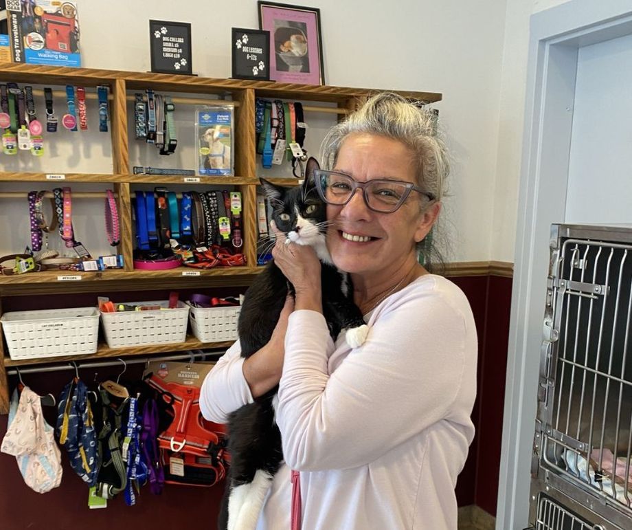 A woman is holding a black and white cat in her arms