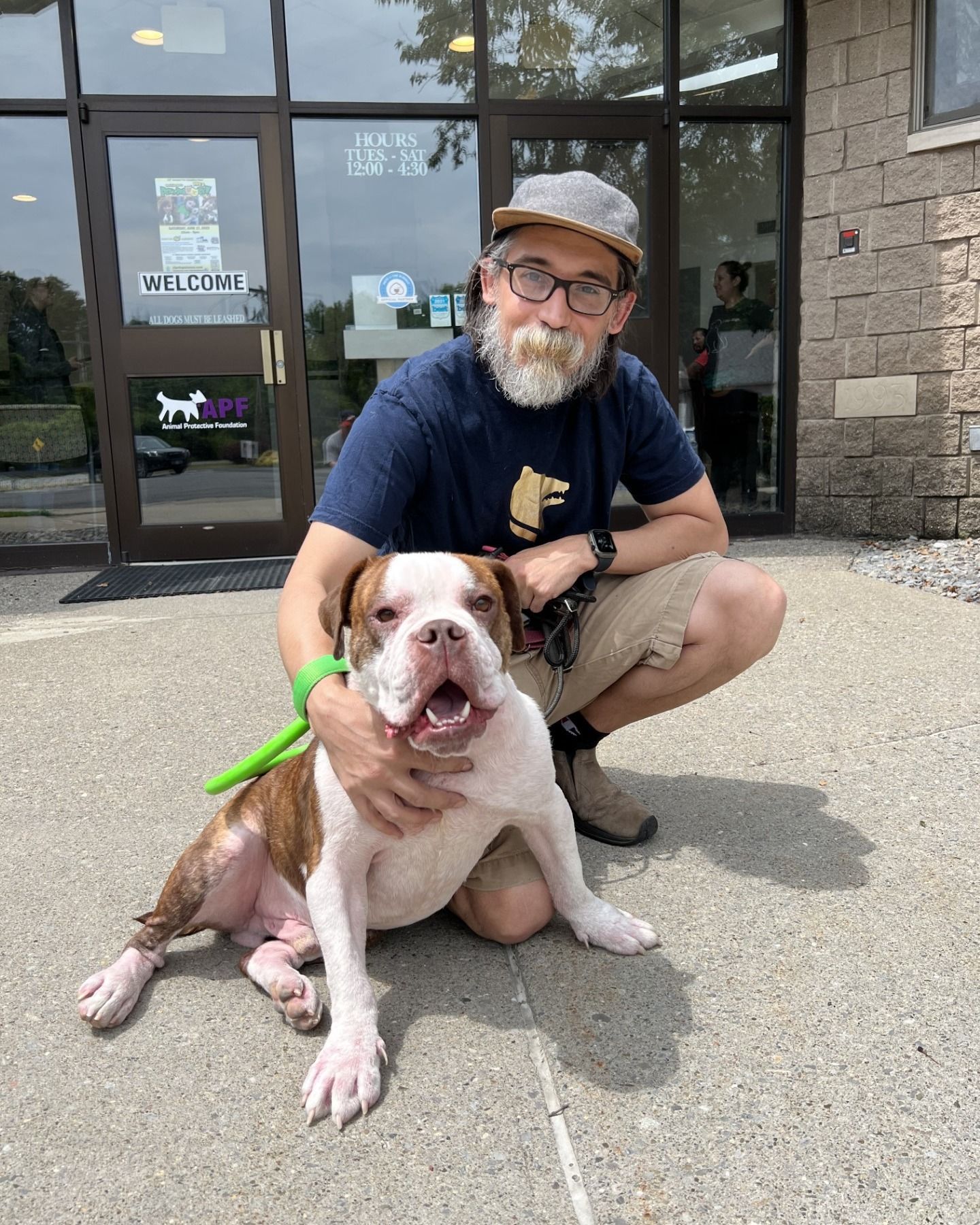 A man is holding a small brown dog in his lap.