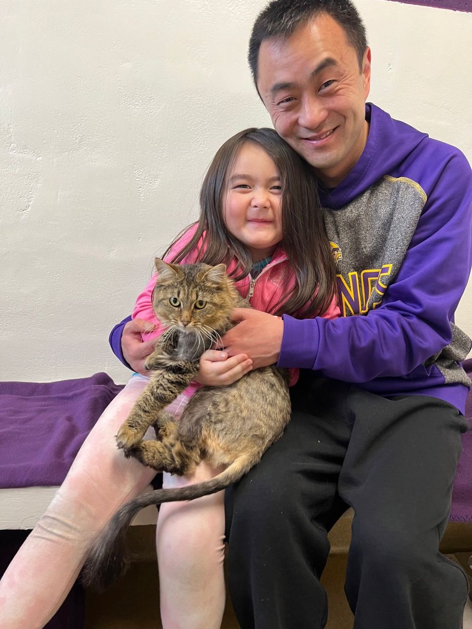 A man and a little girl are holding a cat.