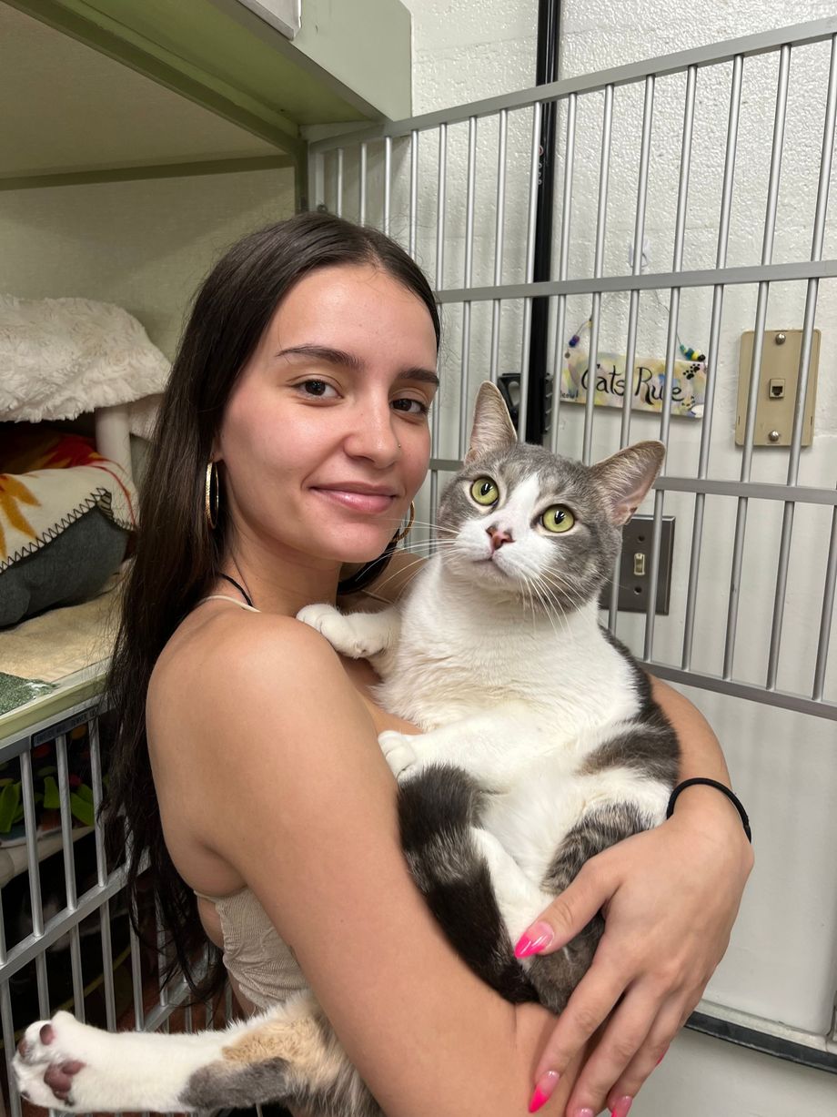 A woman is holding a cat in her arms in a cage.