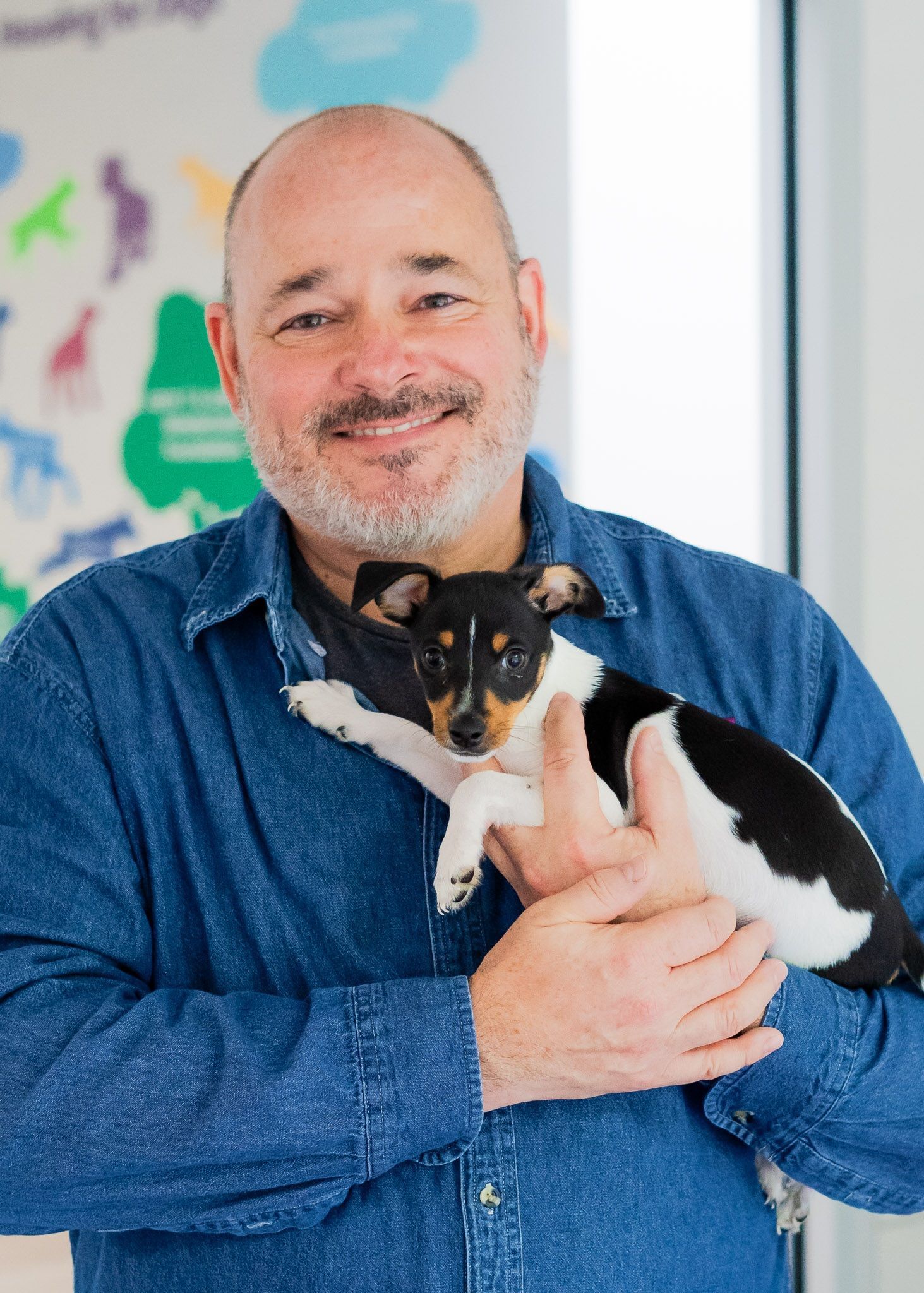 A man is holding a small black and white dog in his arms.