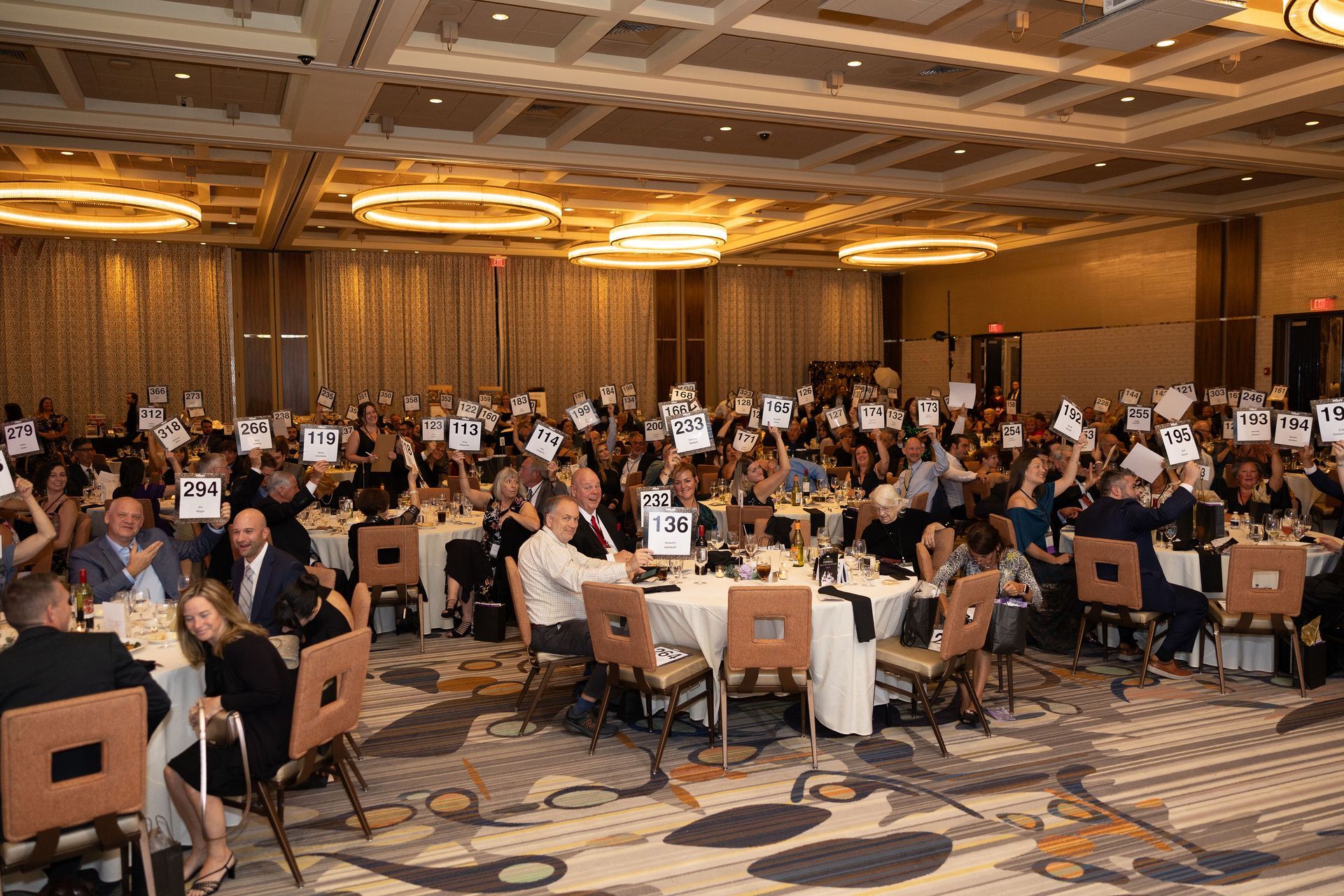 A large group of people are sitting at tables in a large room.