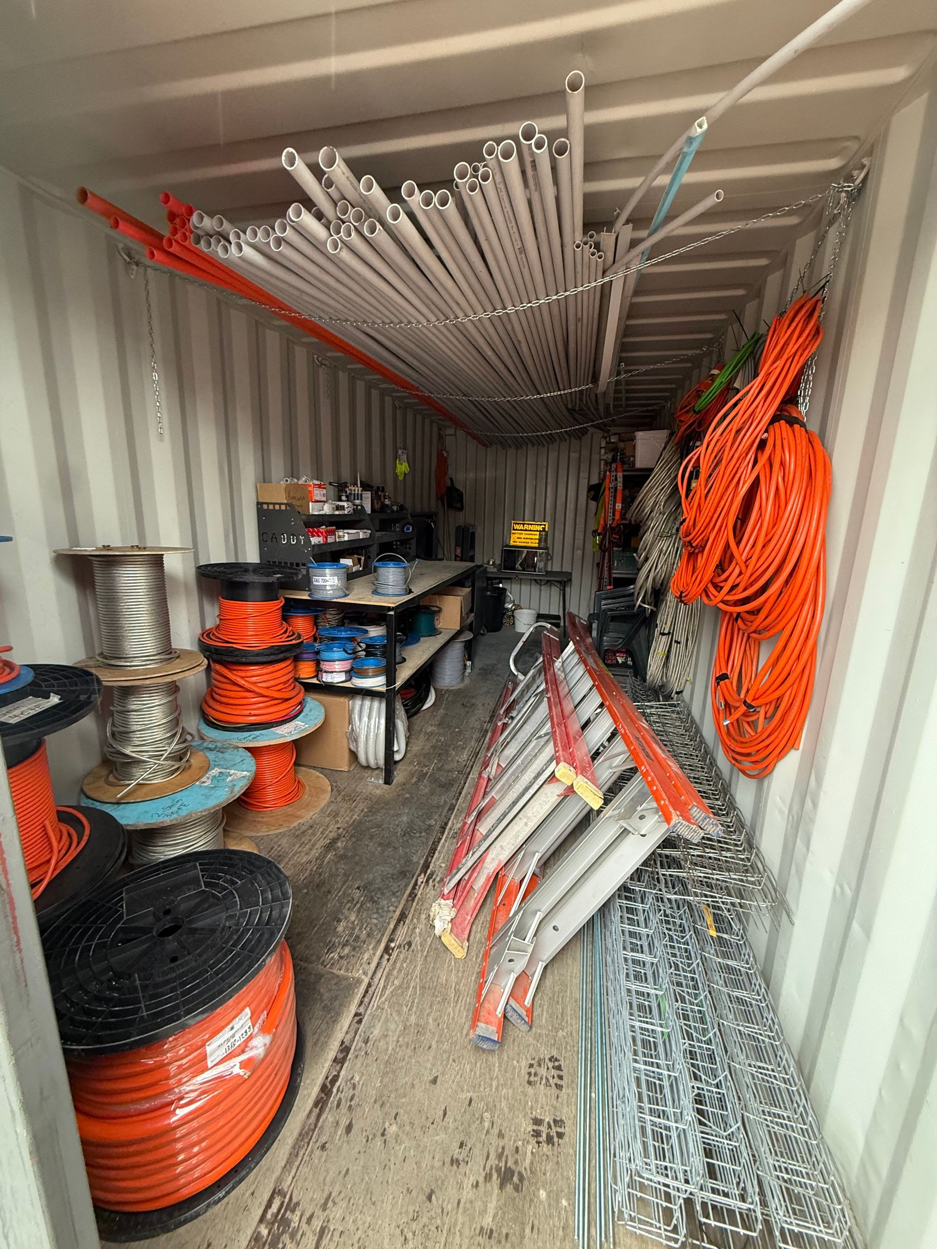 Interior of a shipping container filled with electrical wiring, spools, and tools.