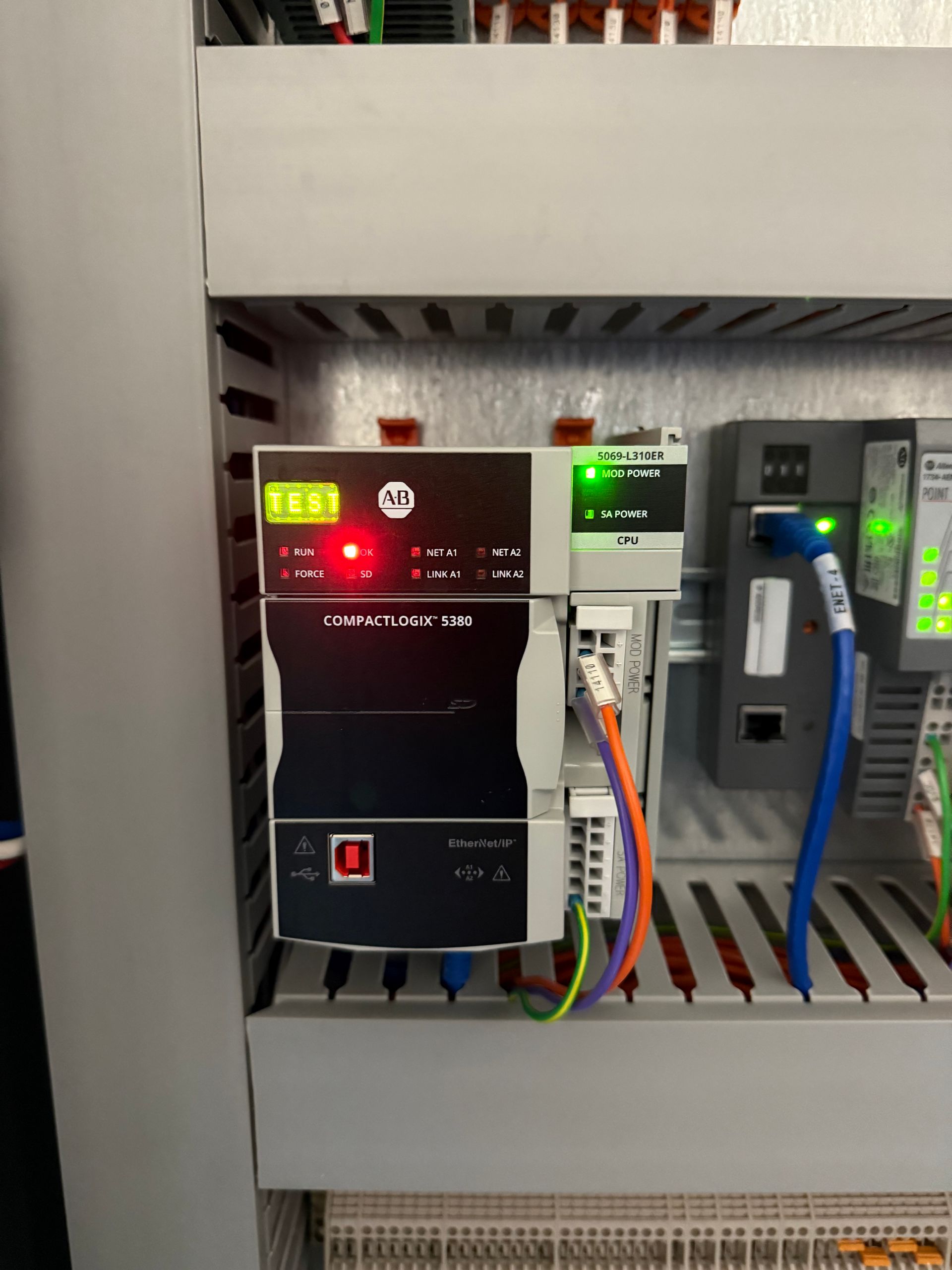 Electrical panel with two black controllers, colored wiring, and an Ethernet cable.