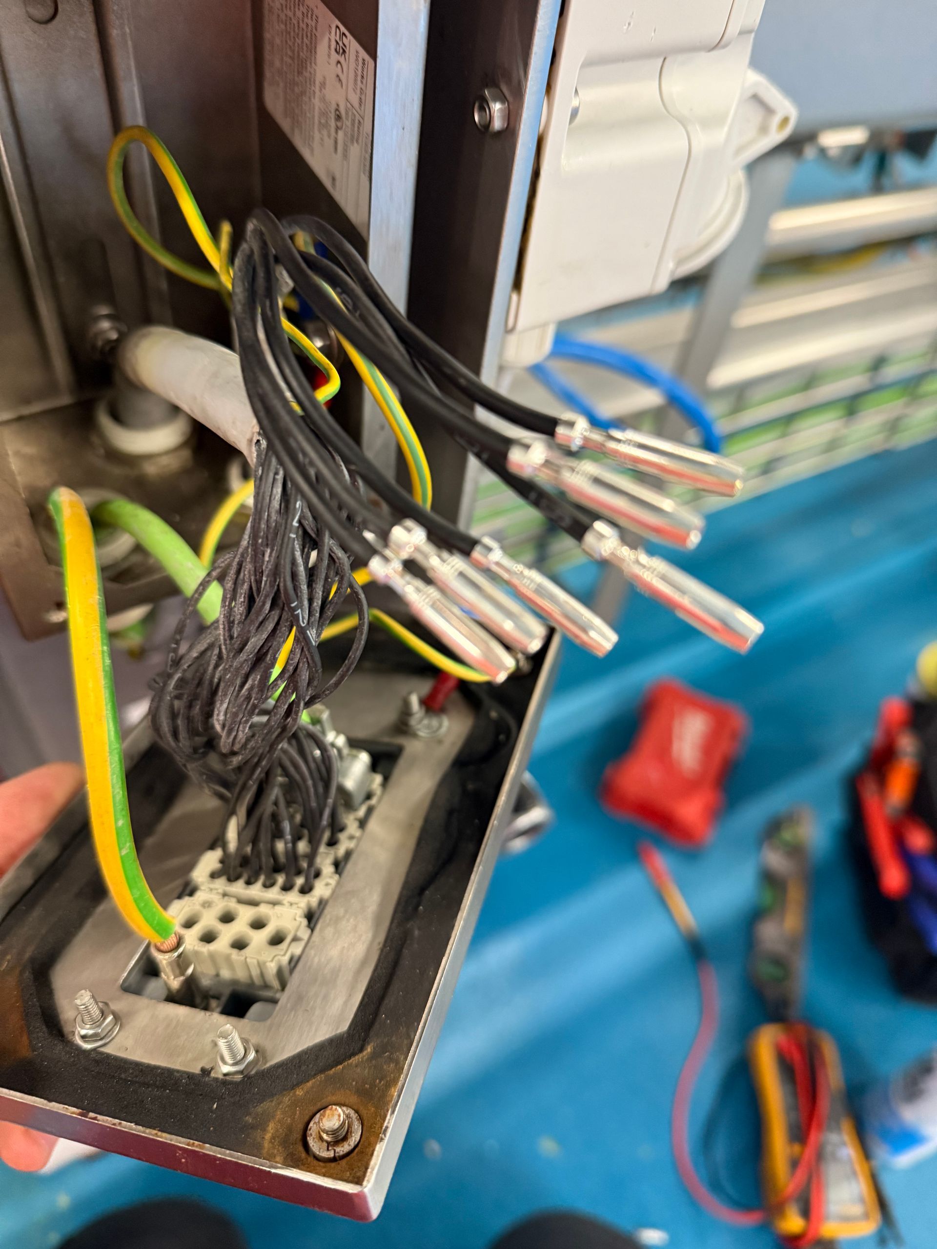 Wiring with crimped terminals inside an electrical panel. Green and yellow ground wire visible.