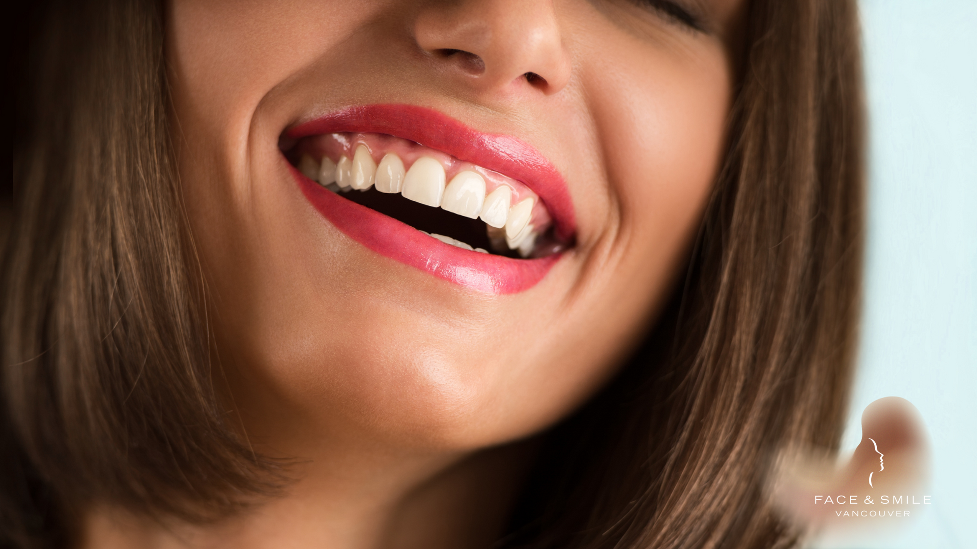 A close up of a woman 's smile with red lipstick.