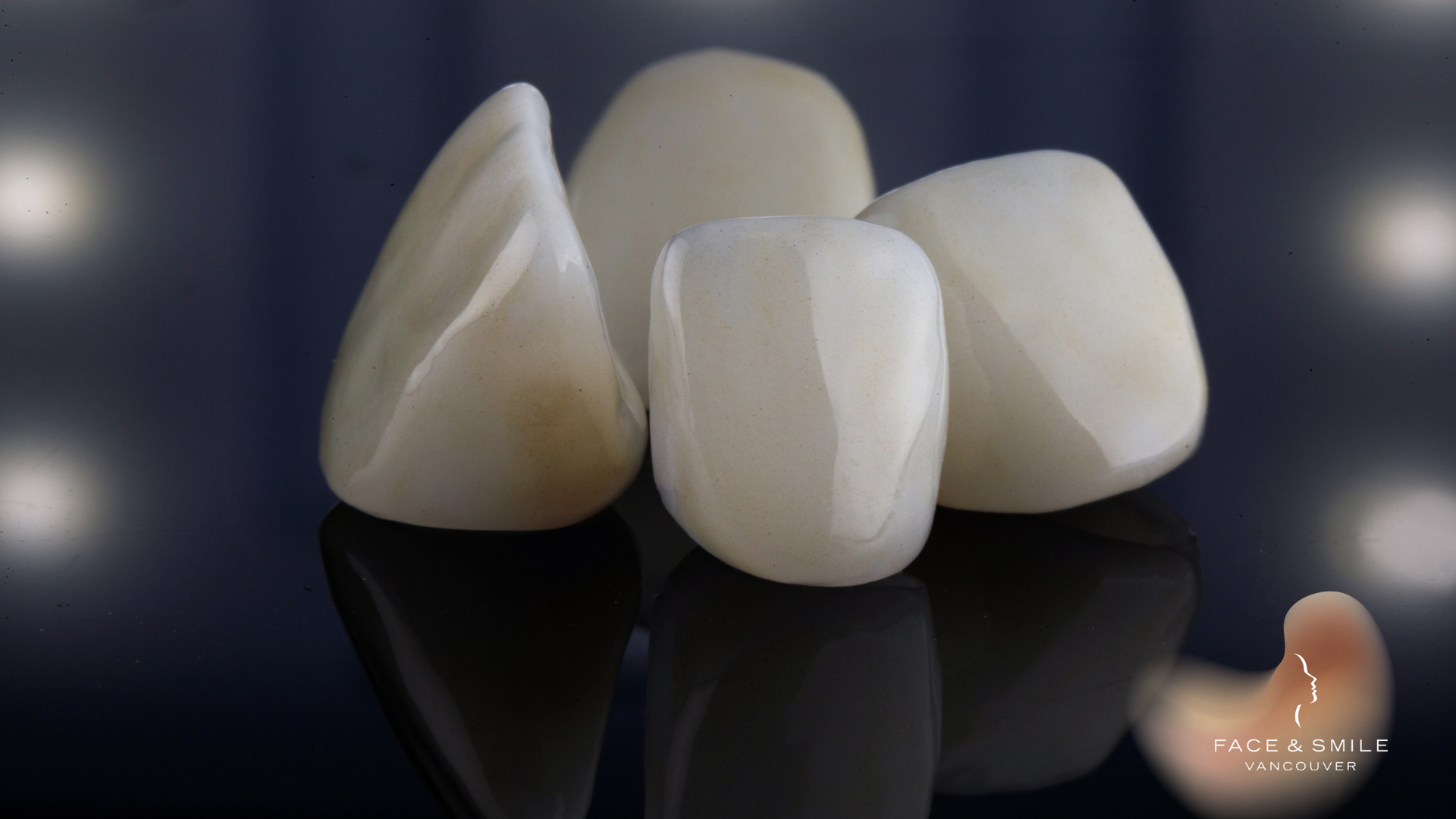 A group of dental crowns are sitting on a black surface.