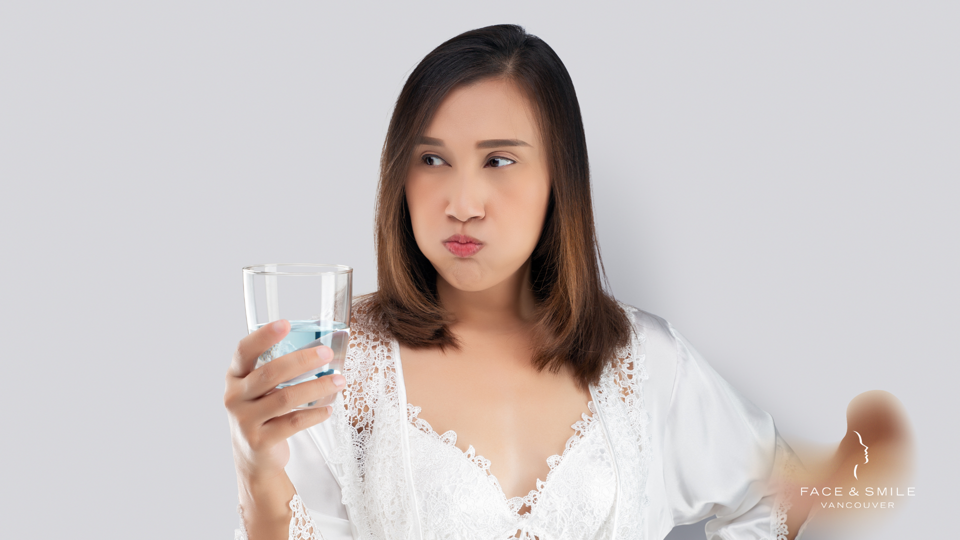 A woman is holding a glass of water in her hand.