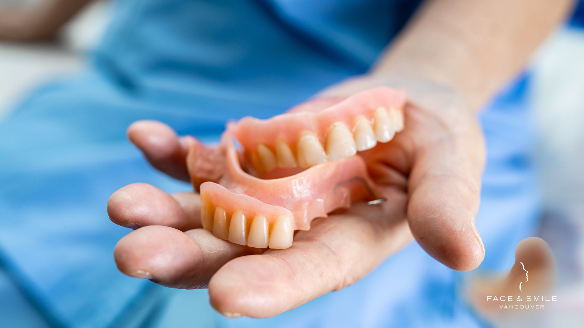 A person is holding a pair of dentures in their hand.