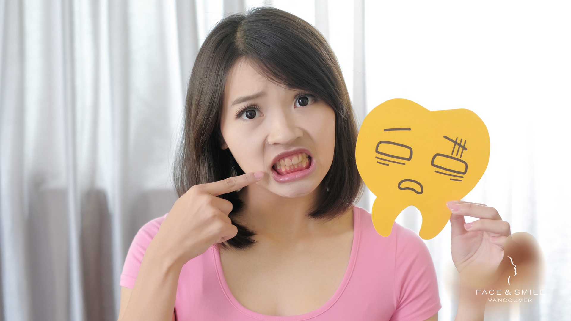 A woman is holding a sign that looks like a tooth and pointing at her teeth.