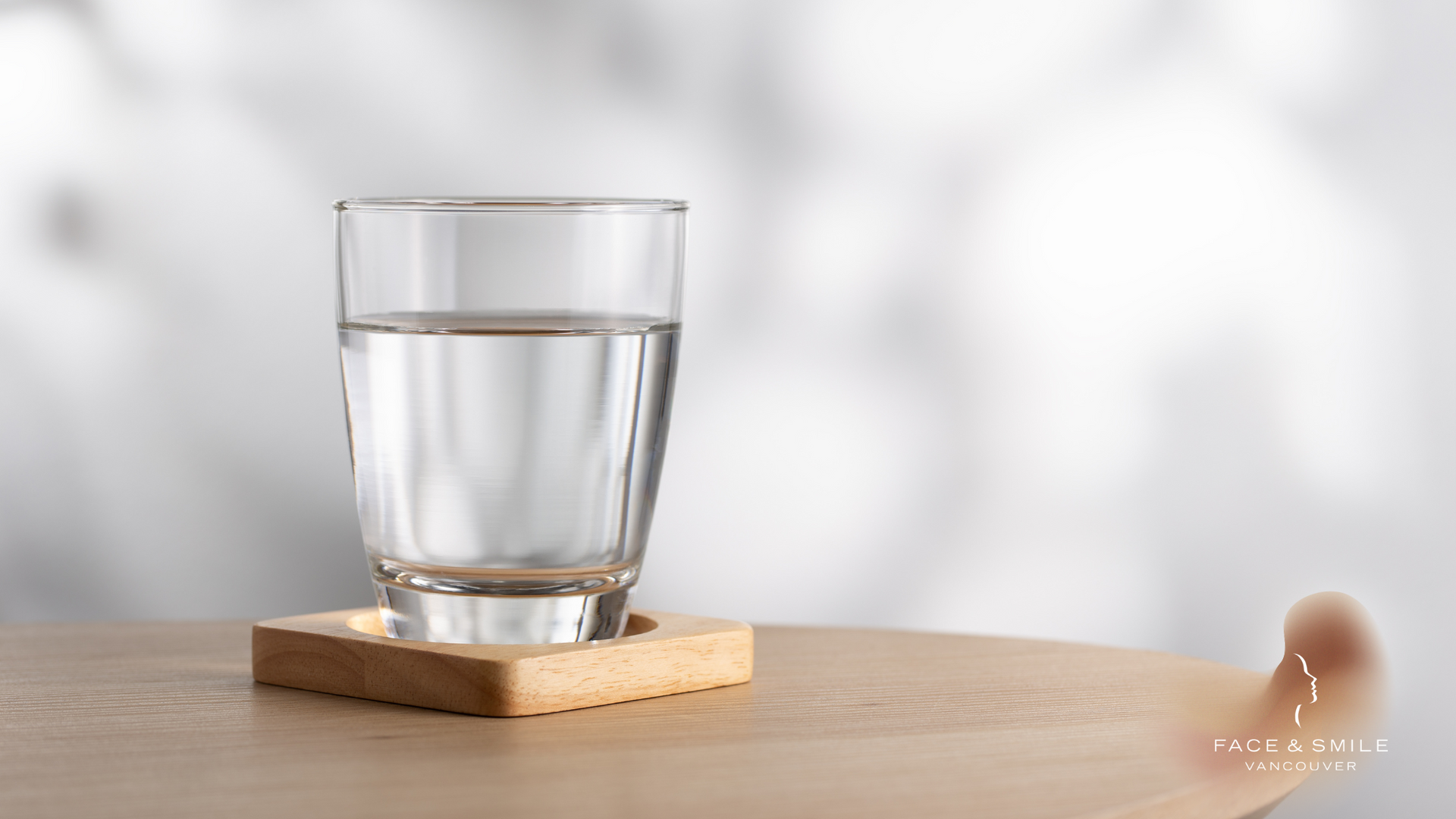 A glass of water is sitting on a wooden table.