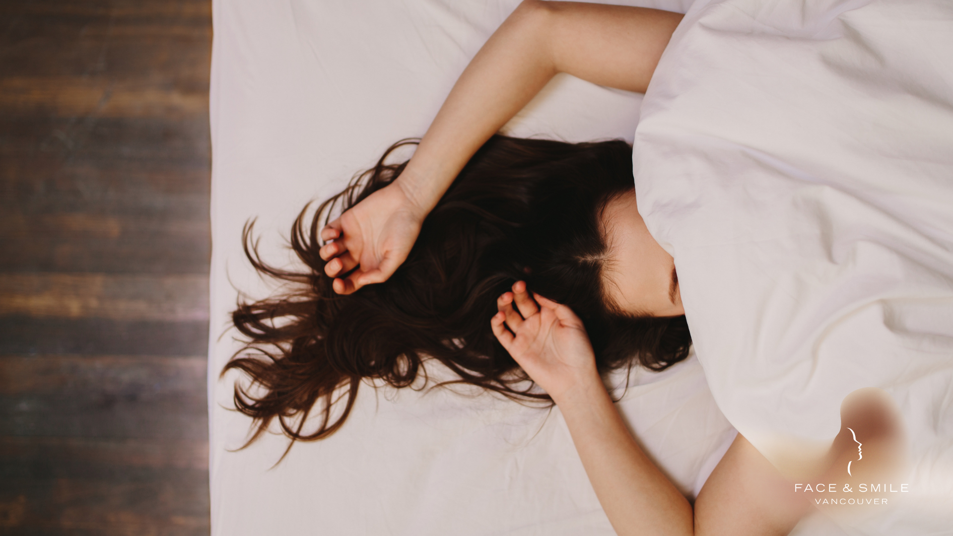 A woman is sleeping on a bed with a white blanket.