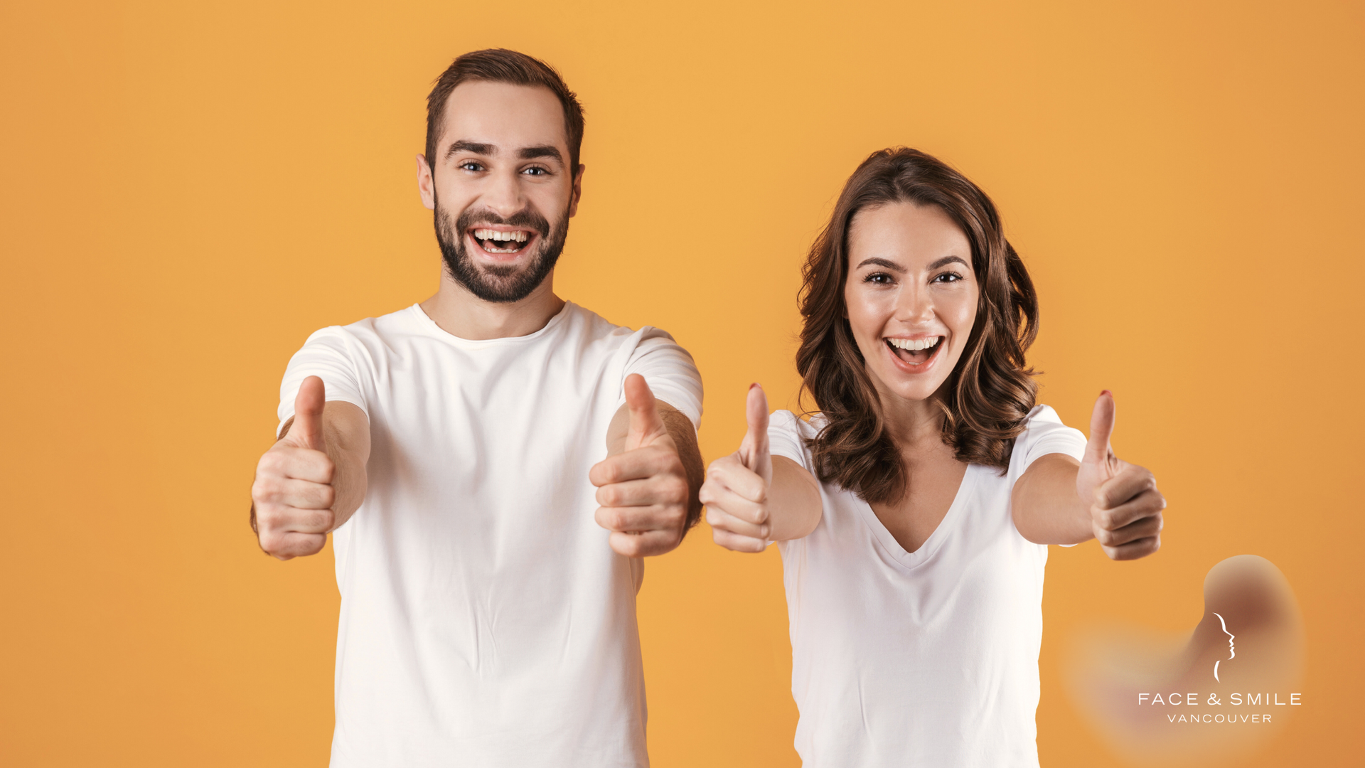 Man and woman in white shirts giving thumbs up, smiling against an orange backdrop.
