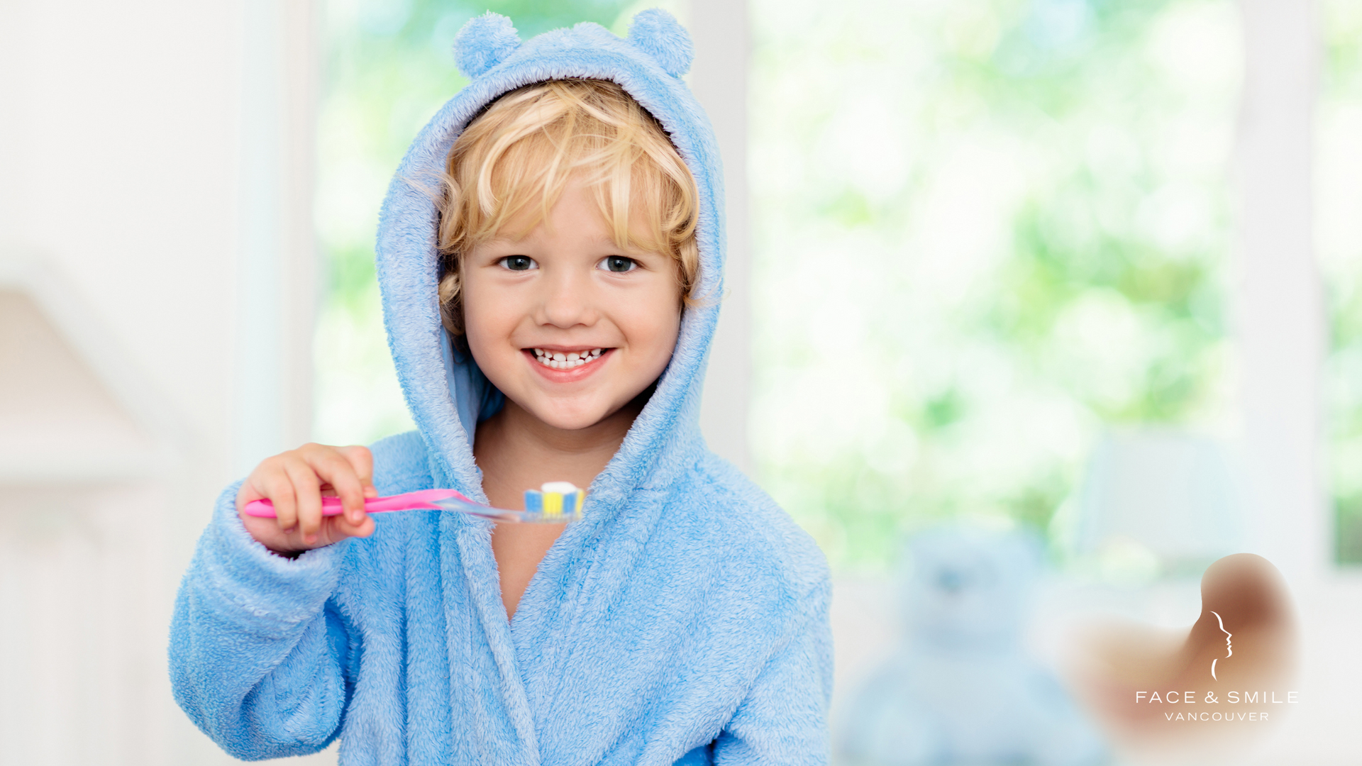 A young boy in a blue robe is brushing his teeth.