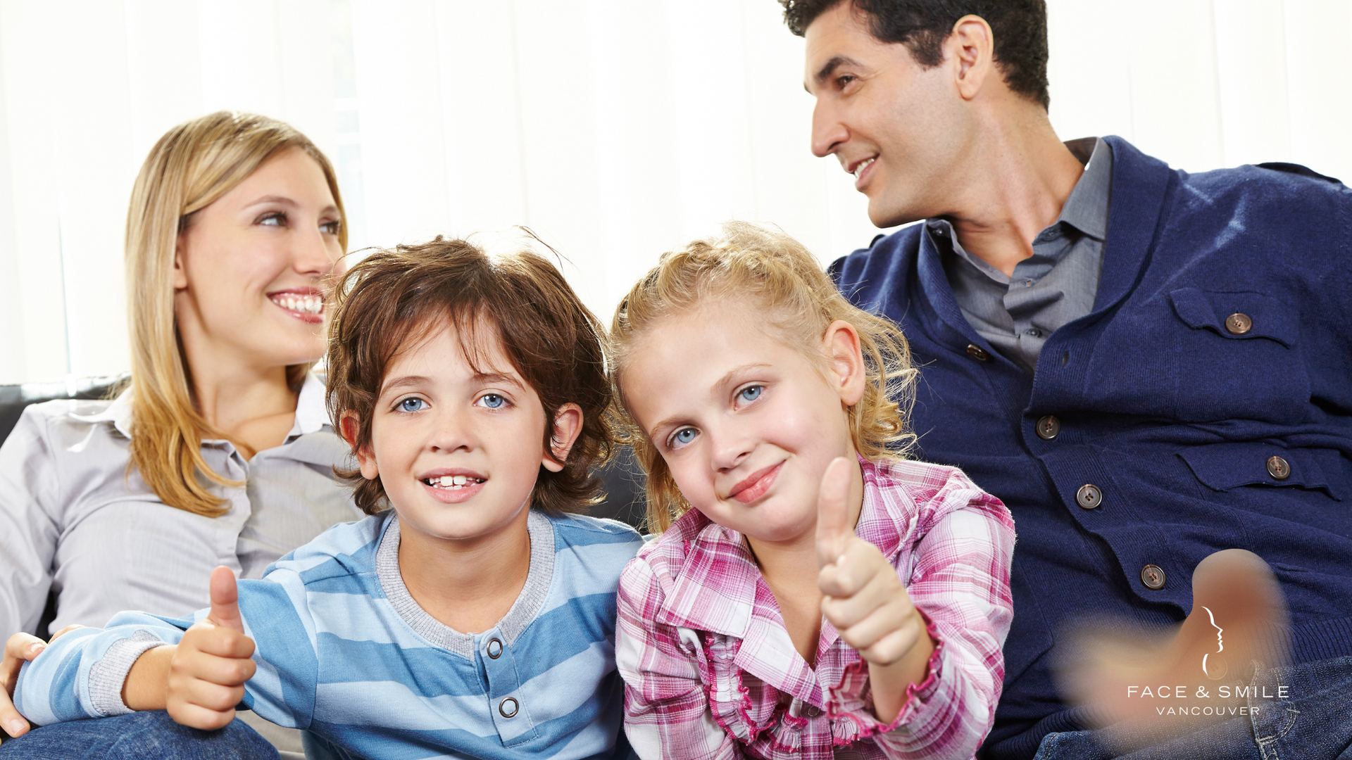 A family is sitting on a couch and giving a thumbs up