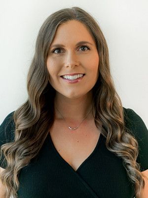A woman wearing a black shirt and a necklace is smiling for the camera.