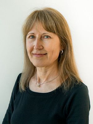 A woman wearing a black shirt and a necklace is smiling for the camera.