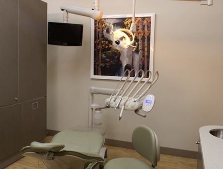 A dental office with a dental chair and a picture on the wall.