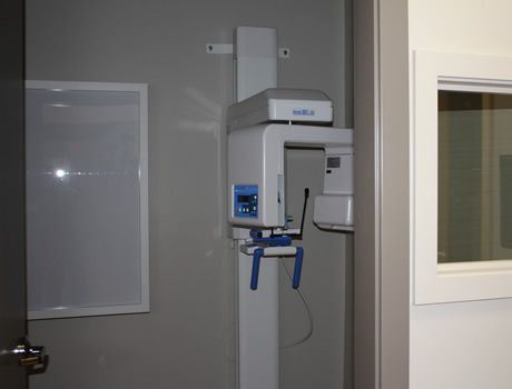 An x-ray machine is sitting in a room next to a window.