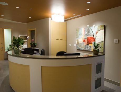 A reception area with a curved counter and a painting on the wall.