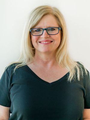 A woman wearing glasses and a black shirt is smiling for the camera.