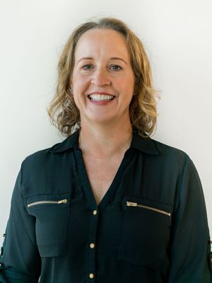 A woman in a black shirt is smiling for the camera.