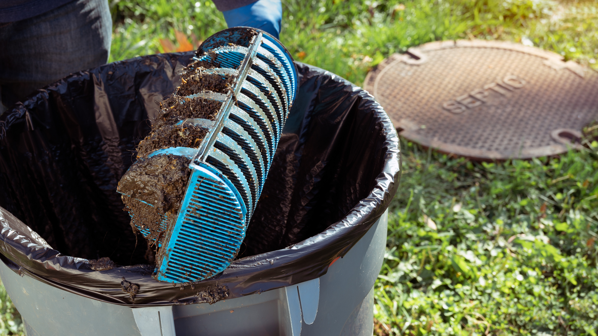 A person is scooping dirt out of a trash can.