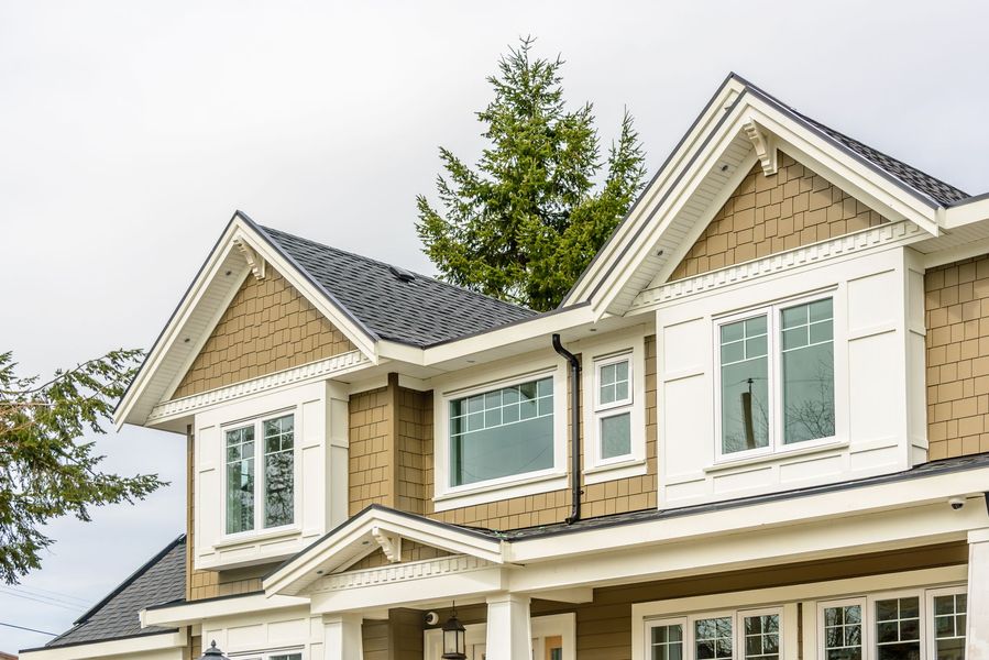 Two-story house with brown siding, white trim, dark roof, and windows.