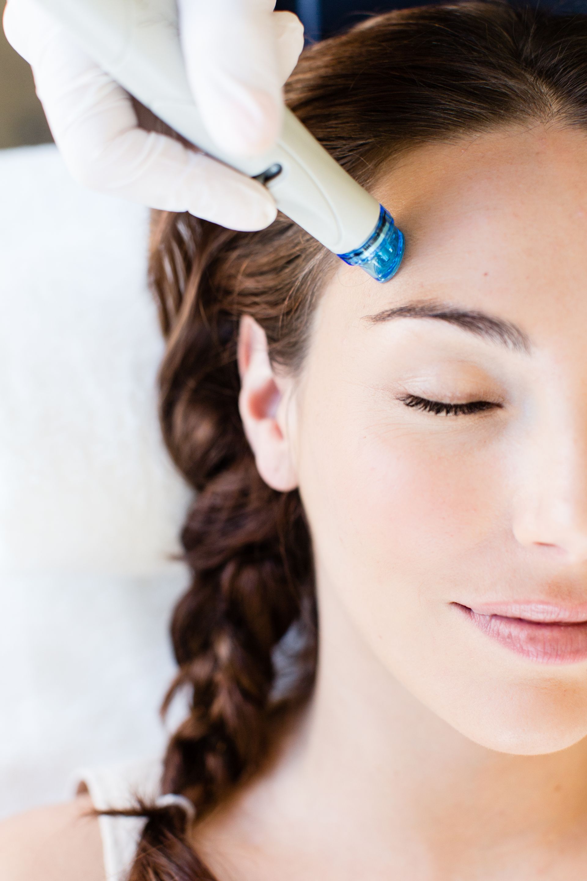 A woman is getting a facial treatment on her forehead.