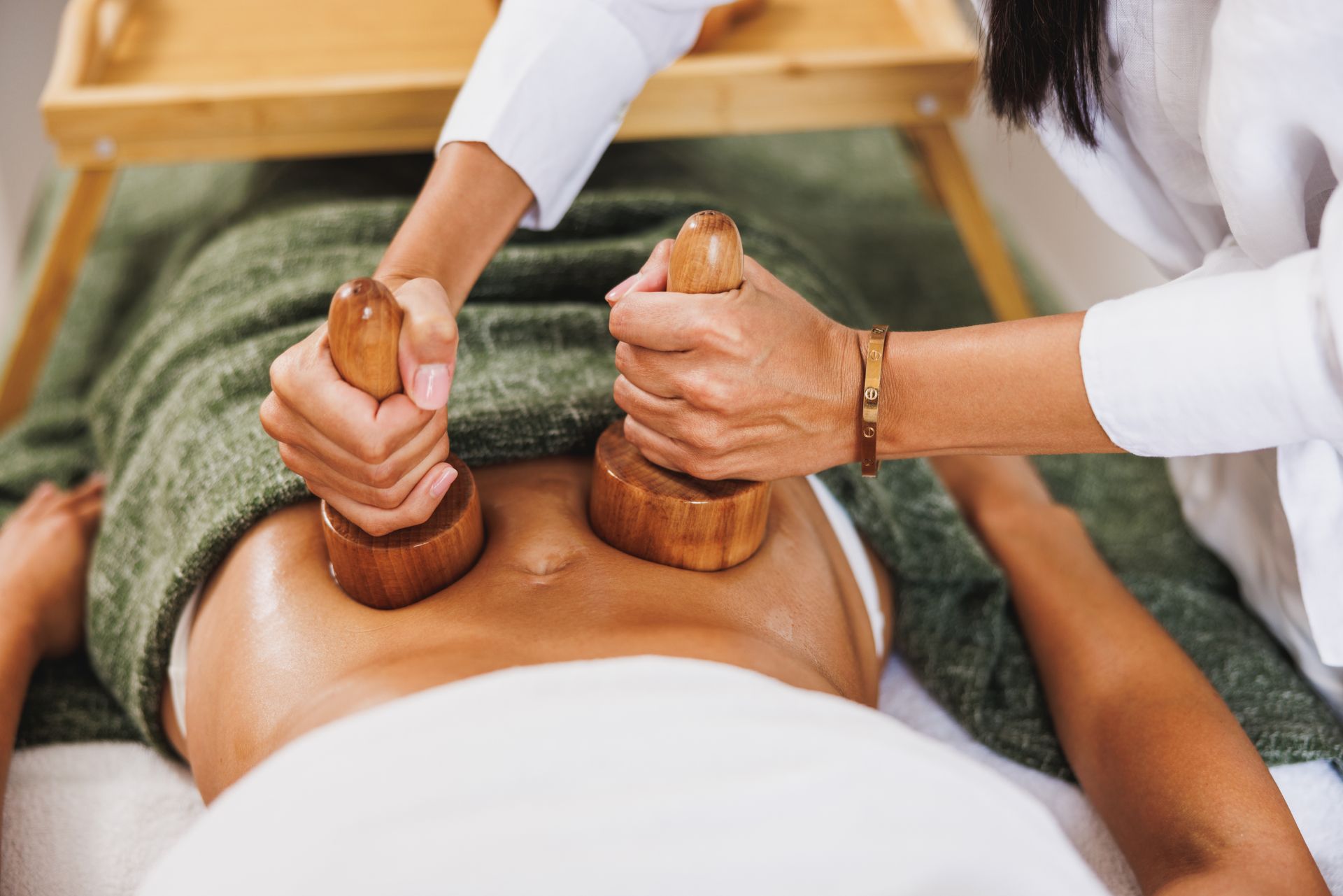 A woman is getting a wooden massage in a spa.