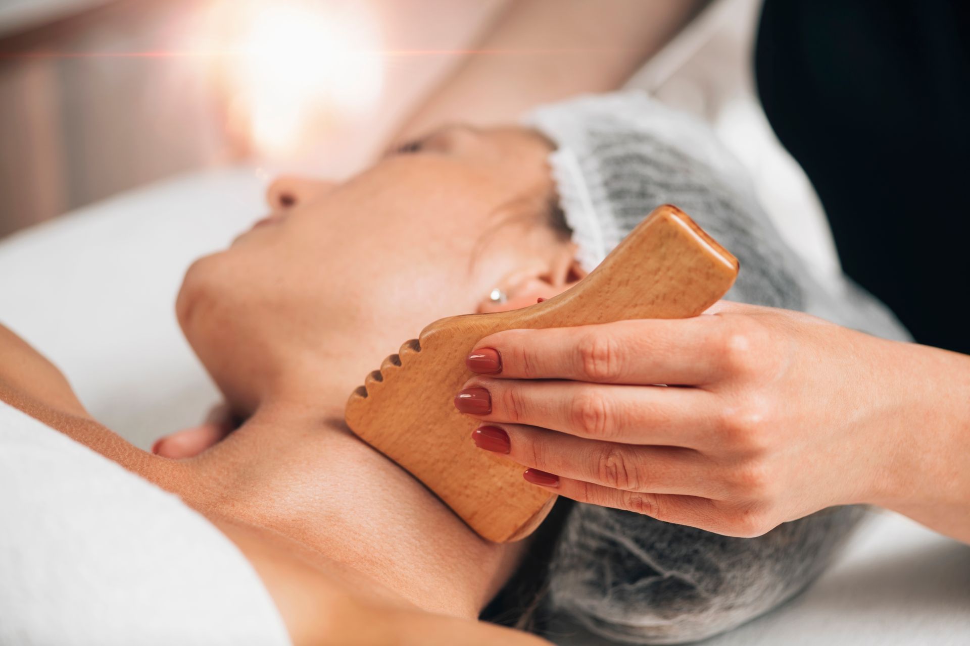 A woman is getting a wooden massage on her neck.