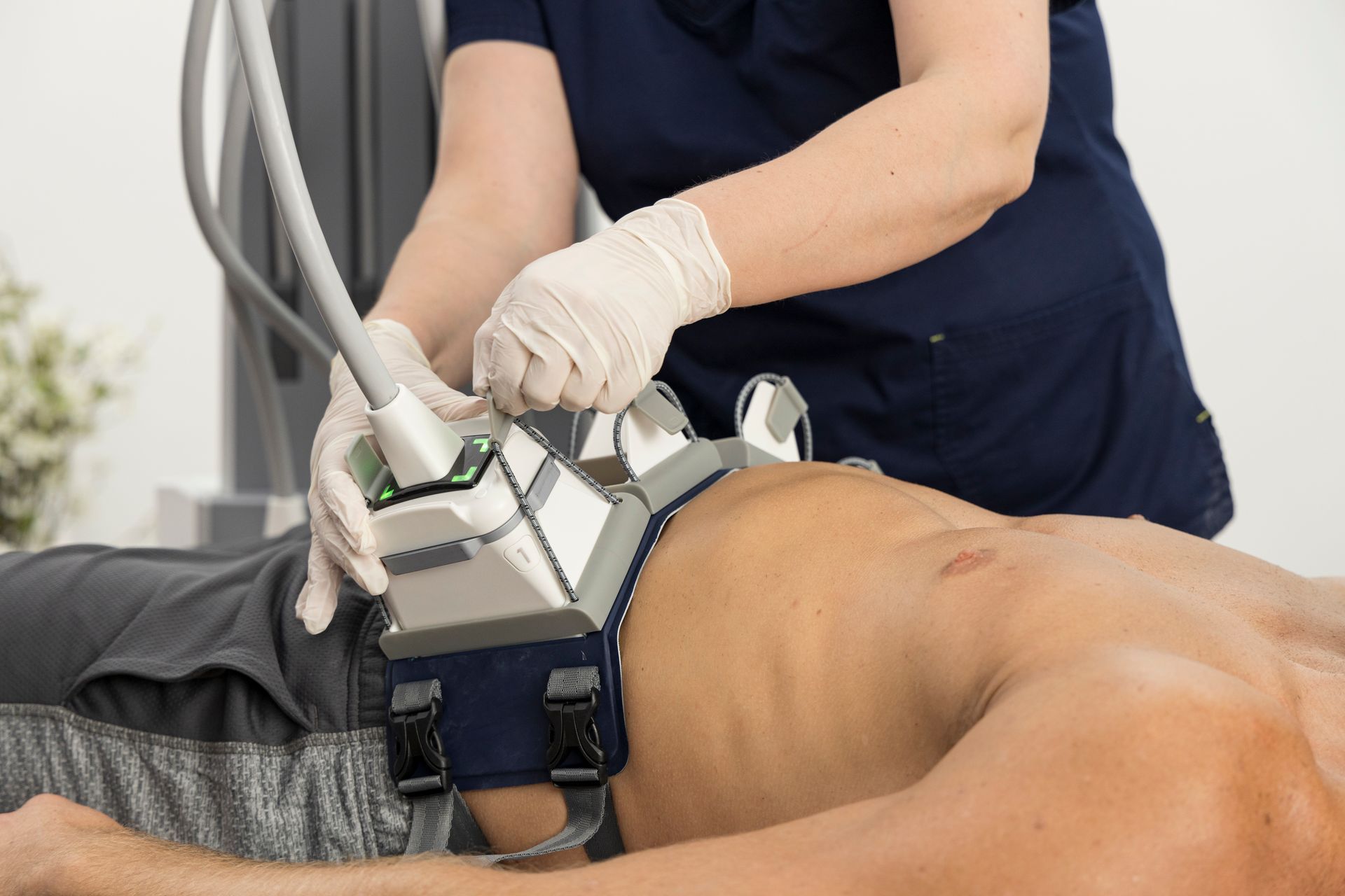A man is laying on a bed getting a surgery on his stomach.