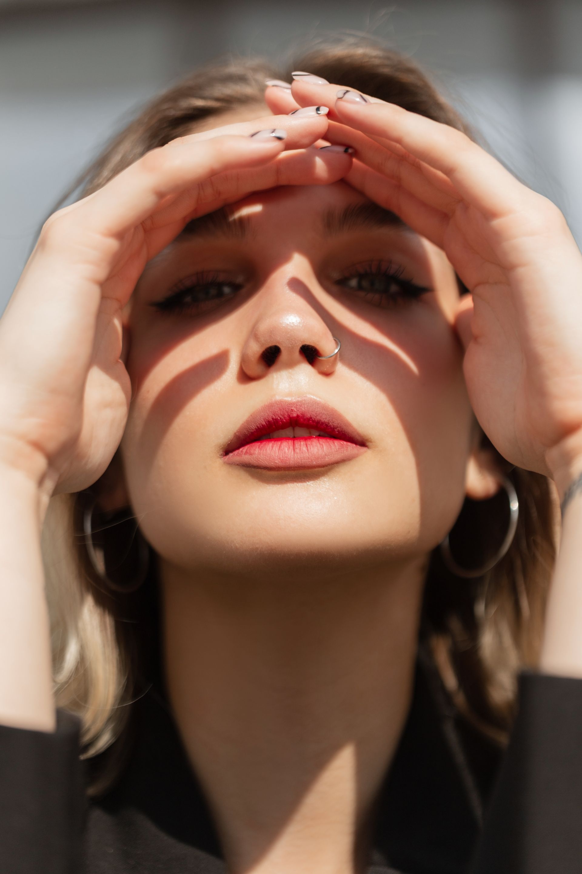 A close up of a woman 's face with her hands on her forehead.