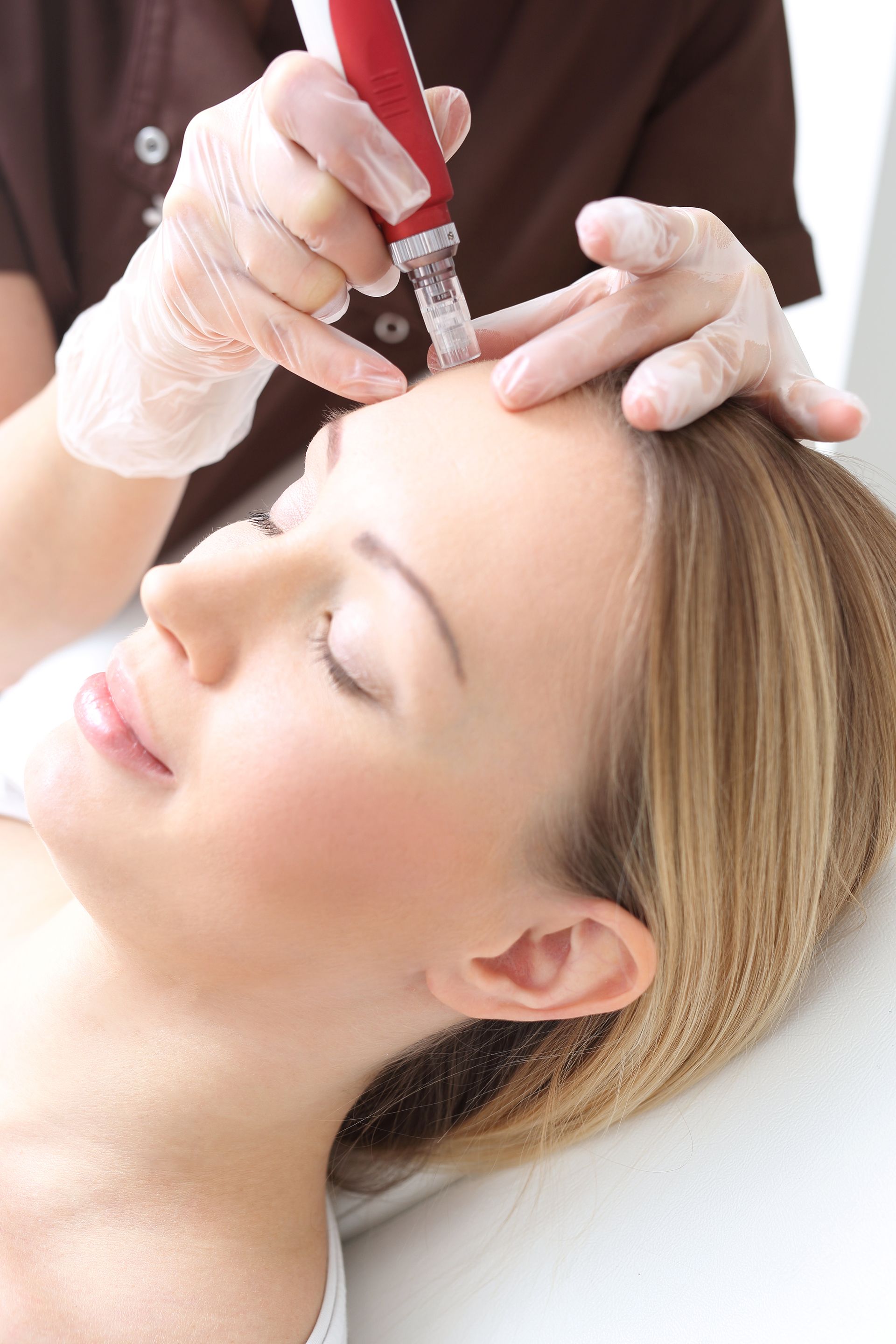 A woman is getting a treatment on her forehead.