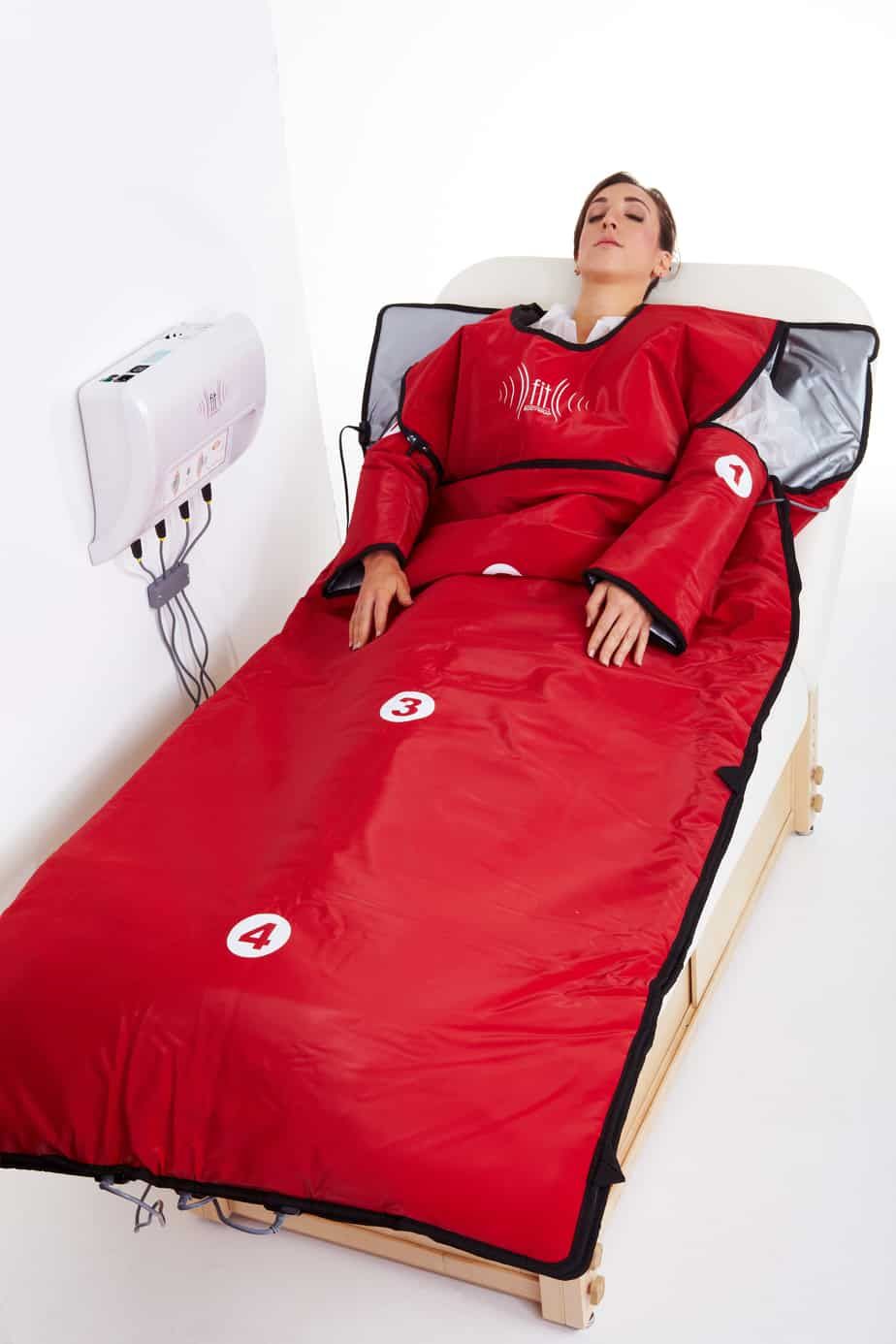 A woman is laying in a red blanket on a bed.