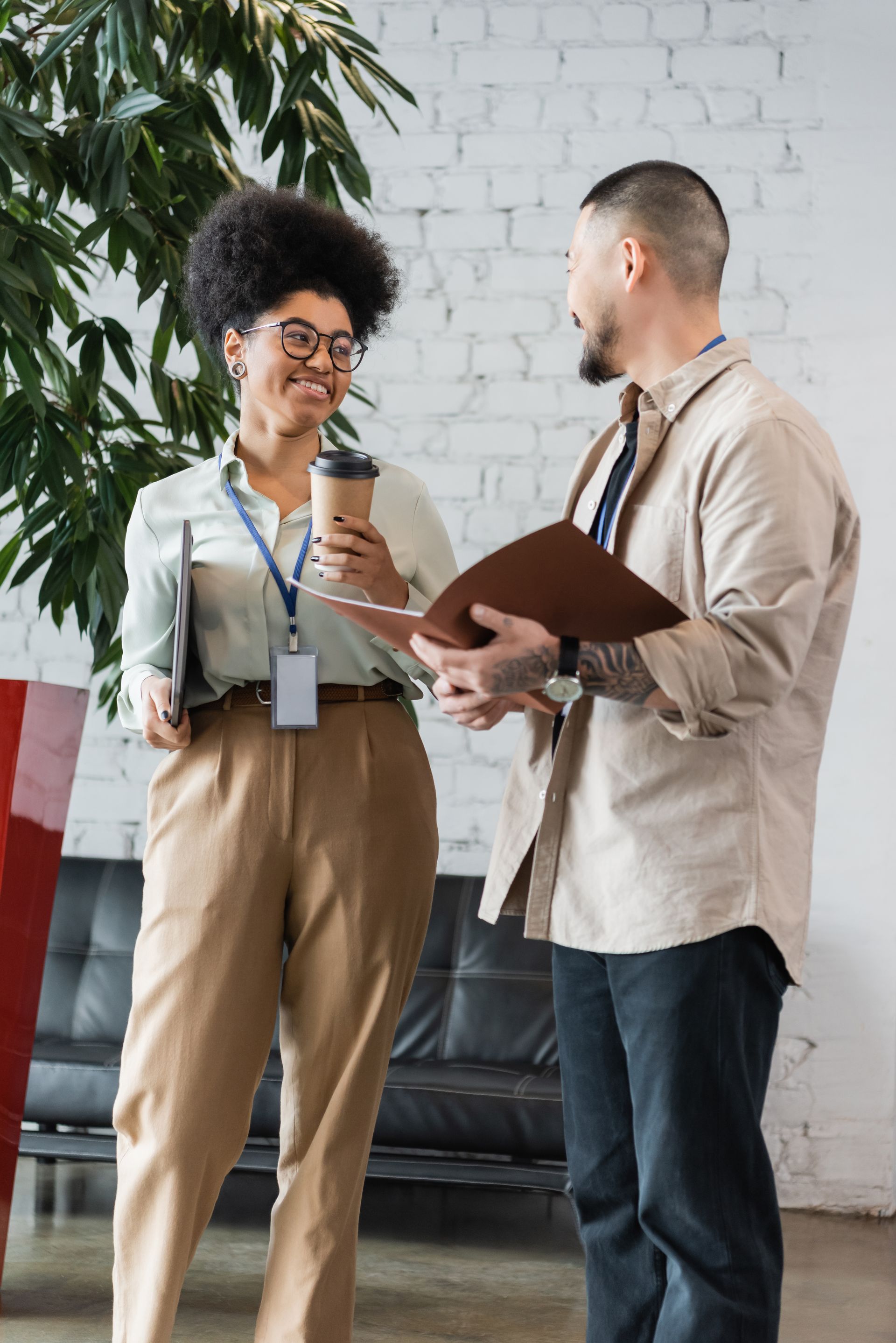 Man and woman in front of an apartment building, talking. The woman is holding a clipboard.