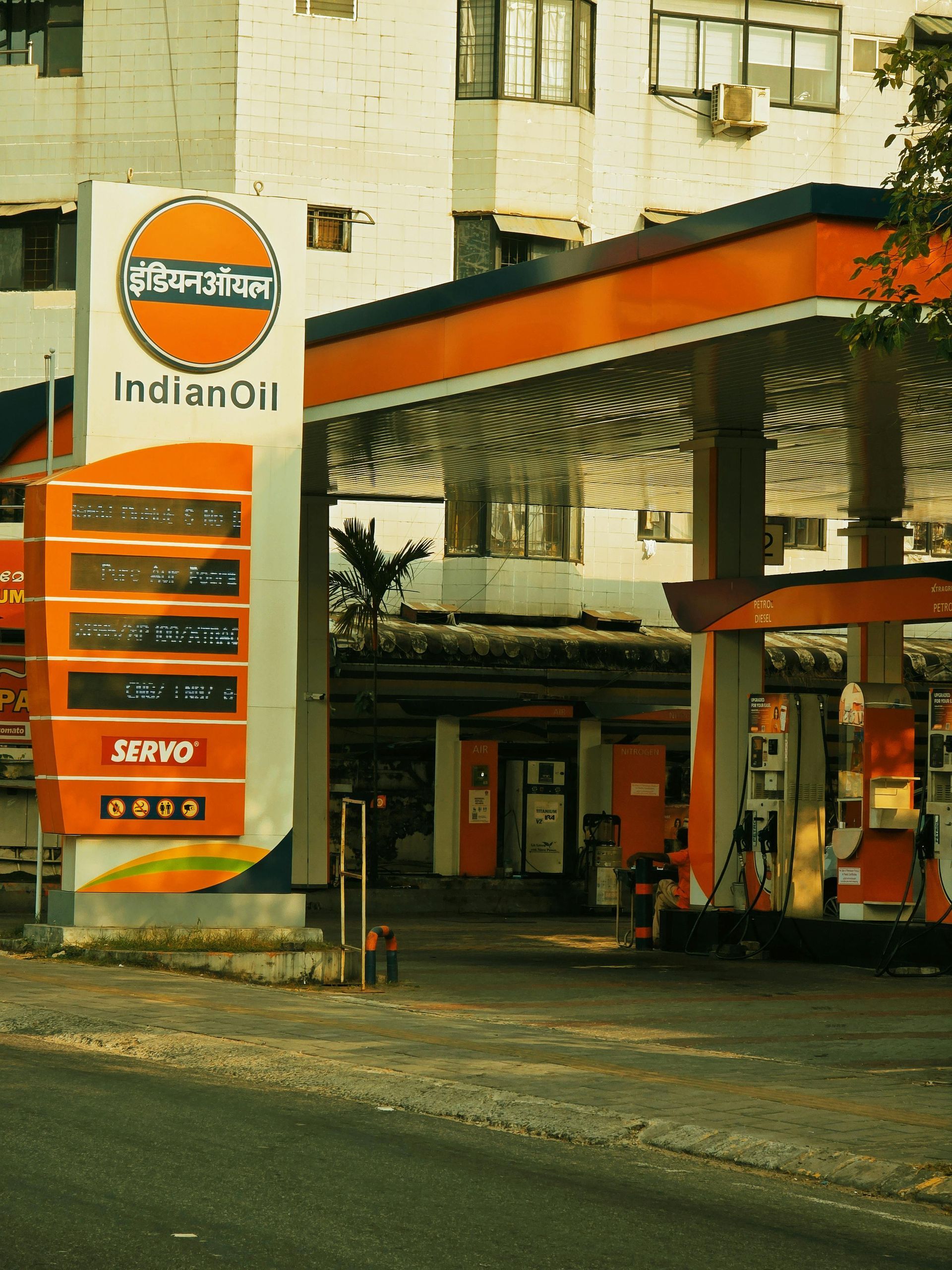 Two warehouse workers in safety vests and hard hats, standing near boxes in a large warehouse.