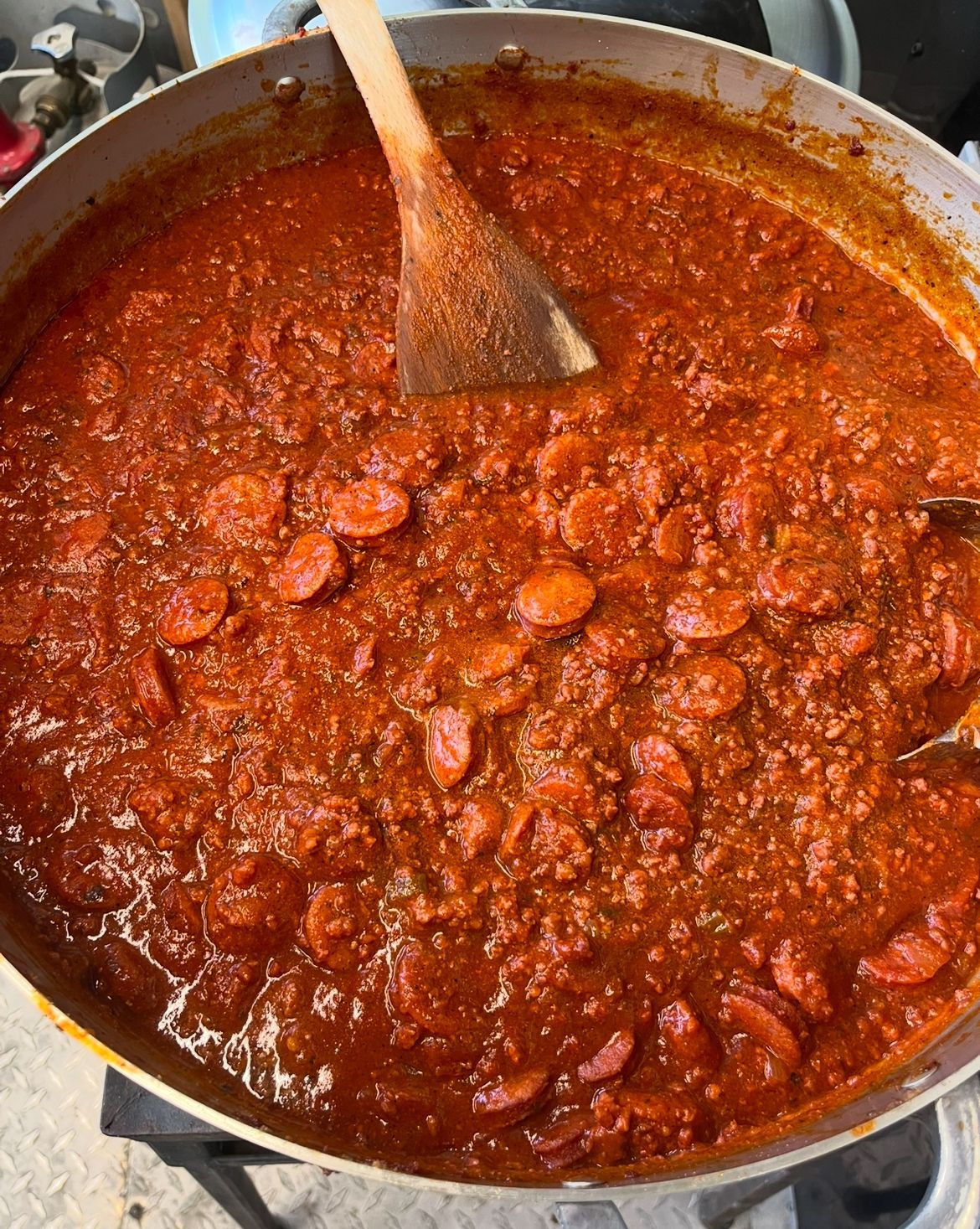 A large pot of chili with a wooden spoon in it.