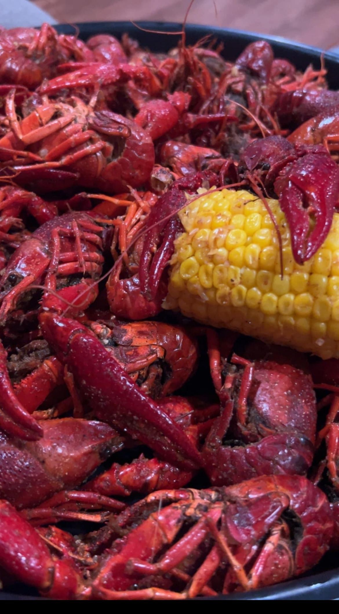 A close up of a plate of crawfish and corn on the cob.