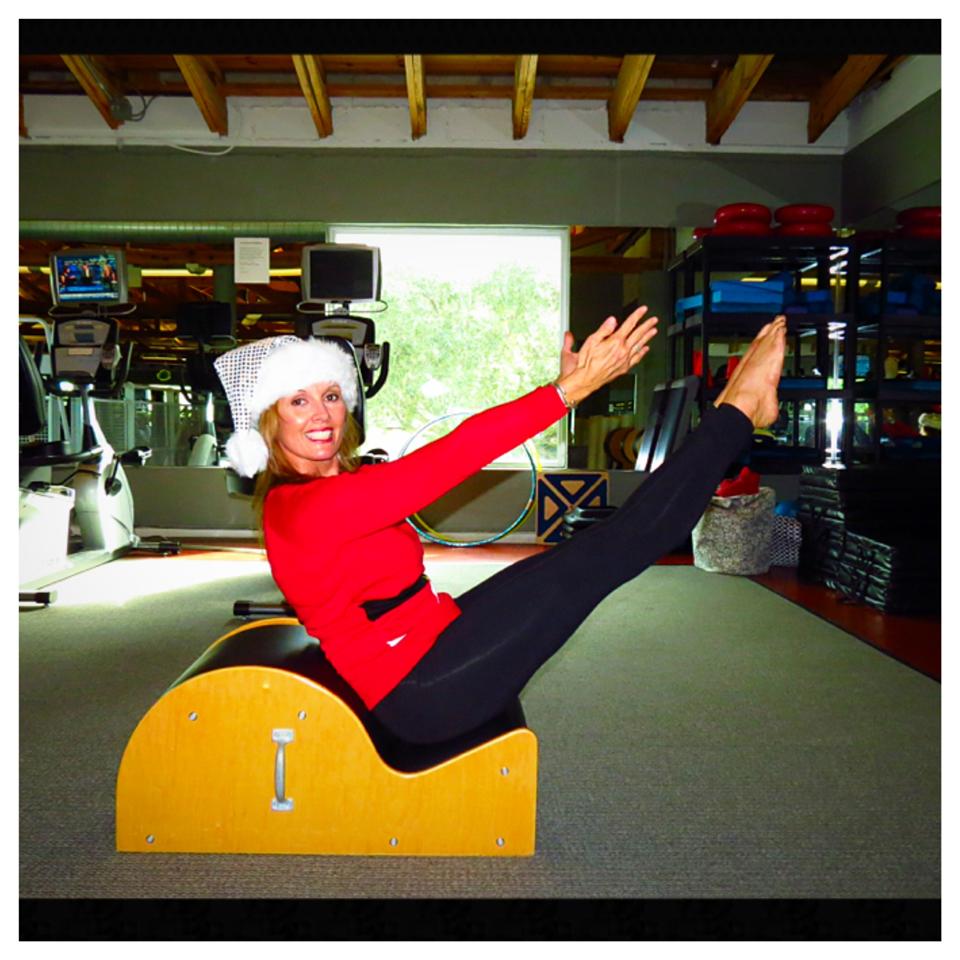 A woman wearing a santa hat is sitting on a barrel in a gym