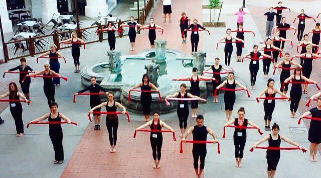 A large group of people are dancing in front of a fountain
