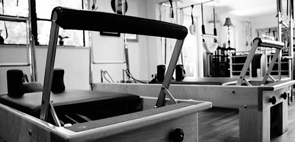 A black and white photo of a pilates machine in a gym.