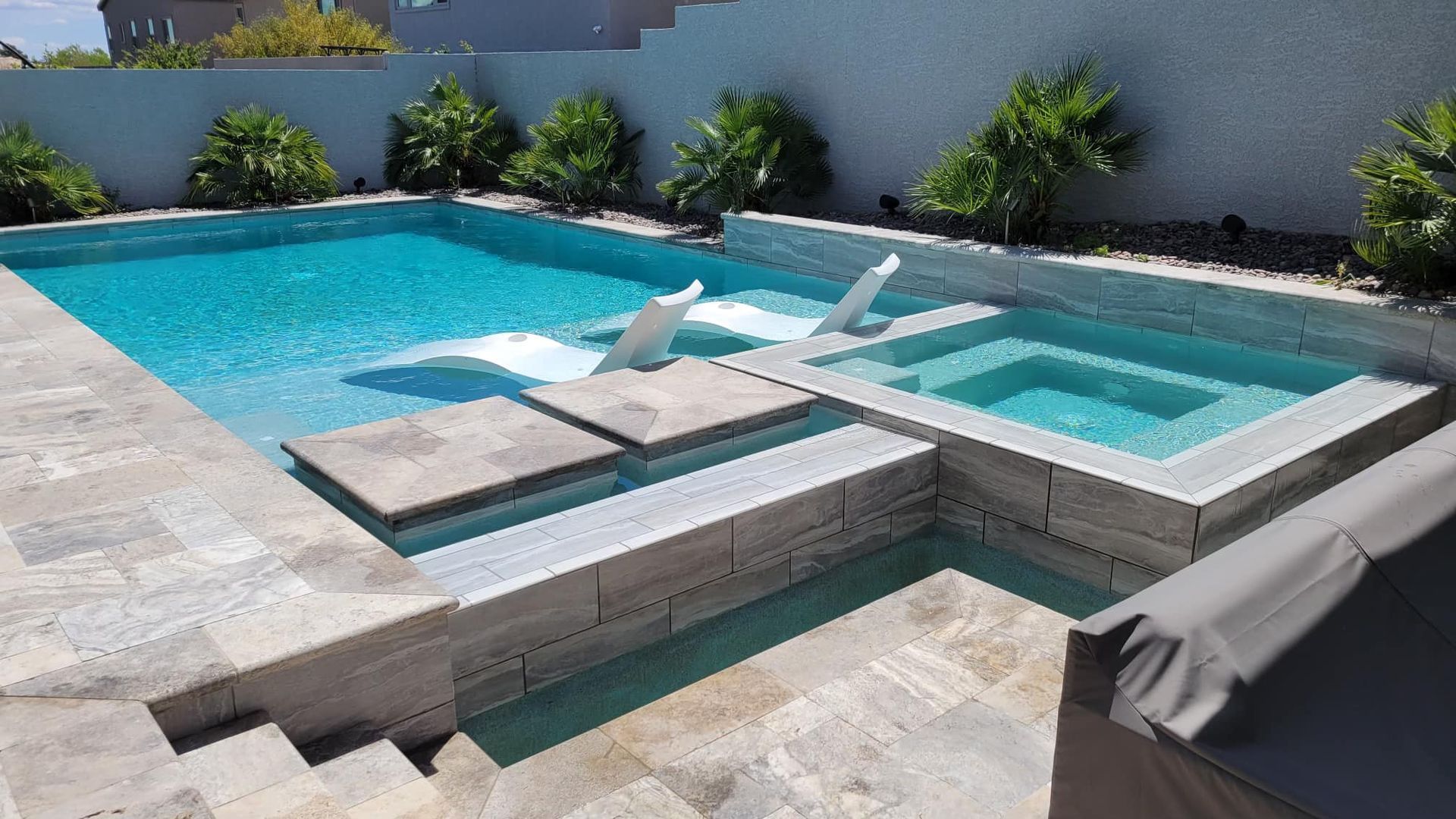 A large swimming pool with two lounge chairs in it