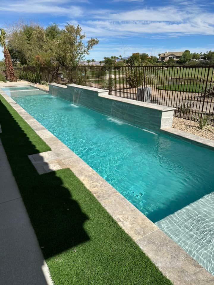 A long swimming pool with a waterfall in the backyard